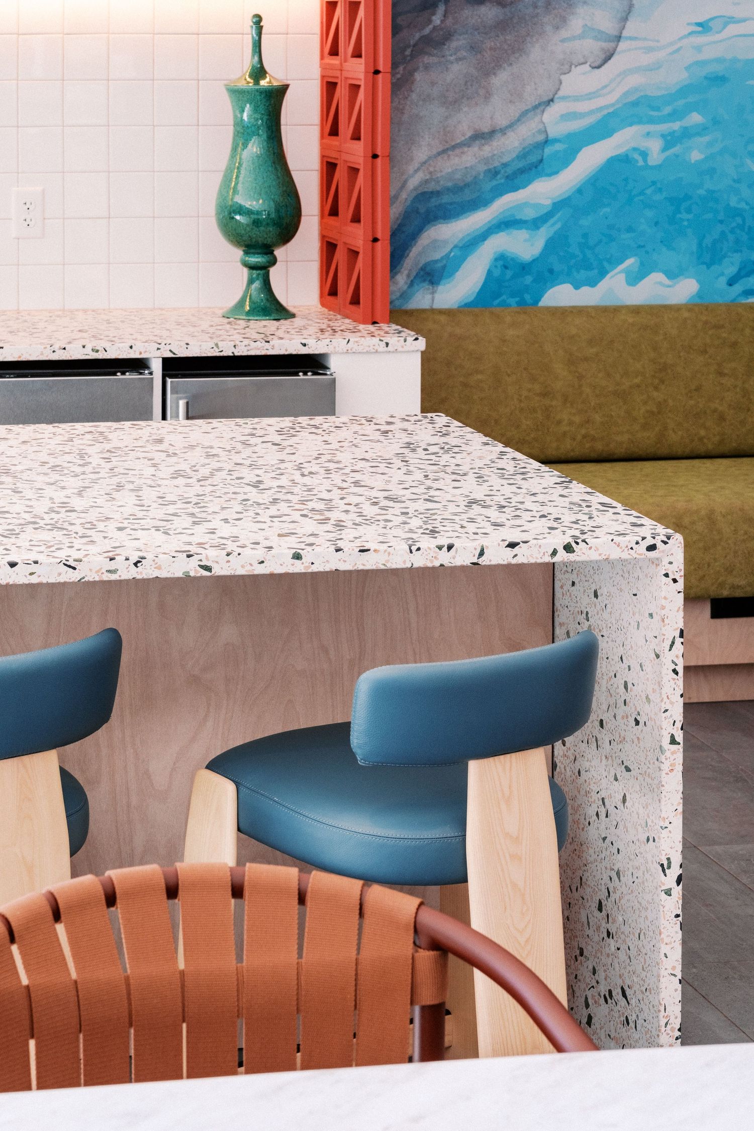 Stylish seating area with terrazzo table, blue chairs and decorative wall art.