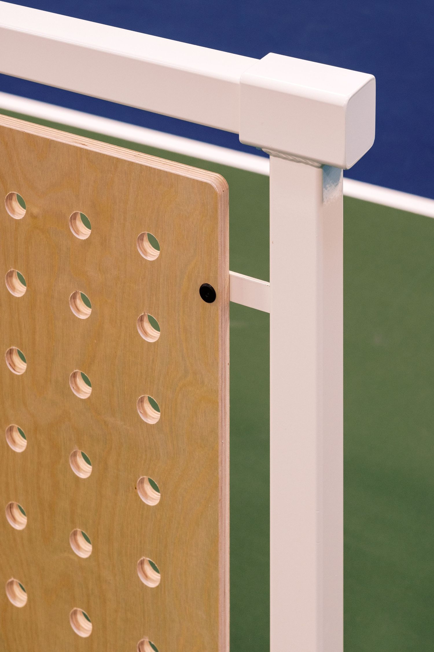 Close-up detail of a wooden pegboard panel with white trim against green and blue walls.