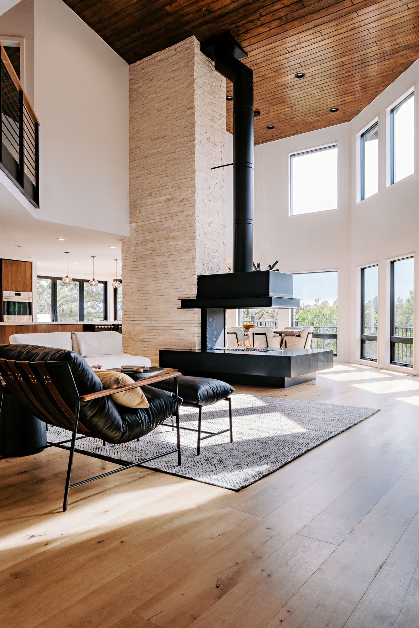 Spacious modern living room with wood ceiling, large windows and open concept design.