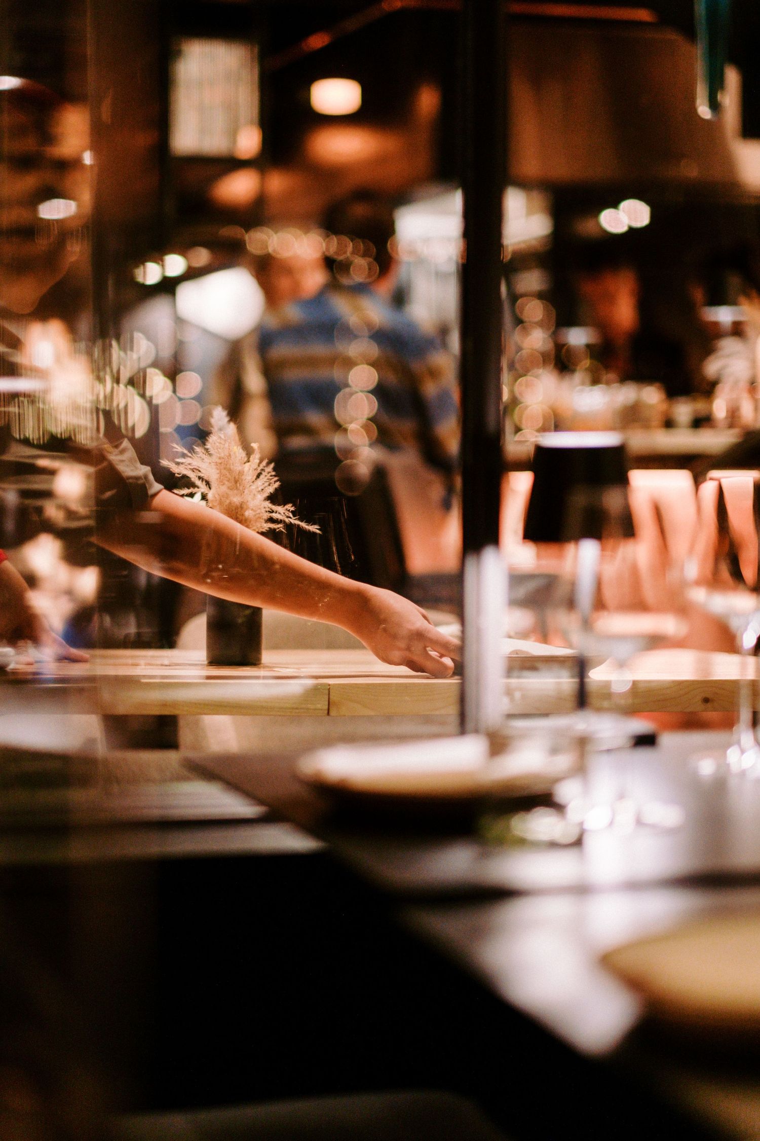 Blurred motion of restaurant service with hands serving plates in warm lighting.
