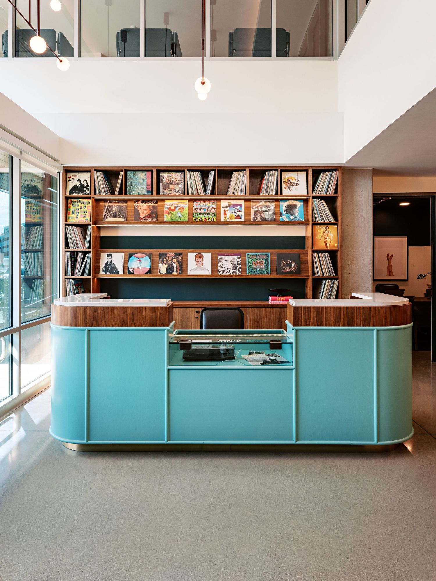 Sleek library interior with turquoise storage units and built-in bookshelves along white walls.