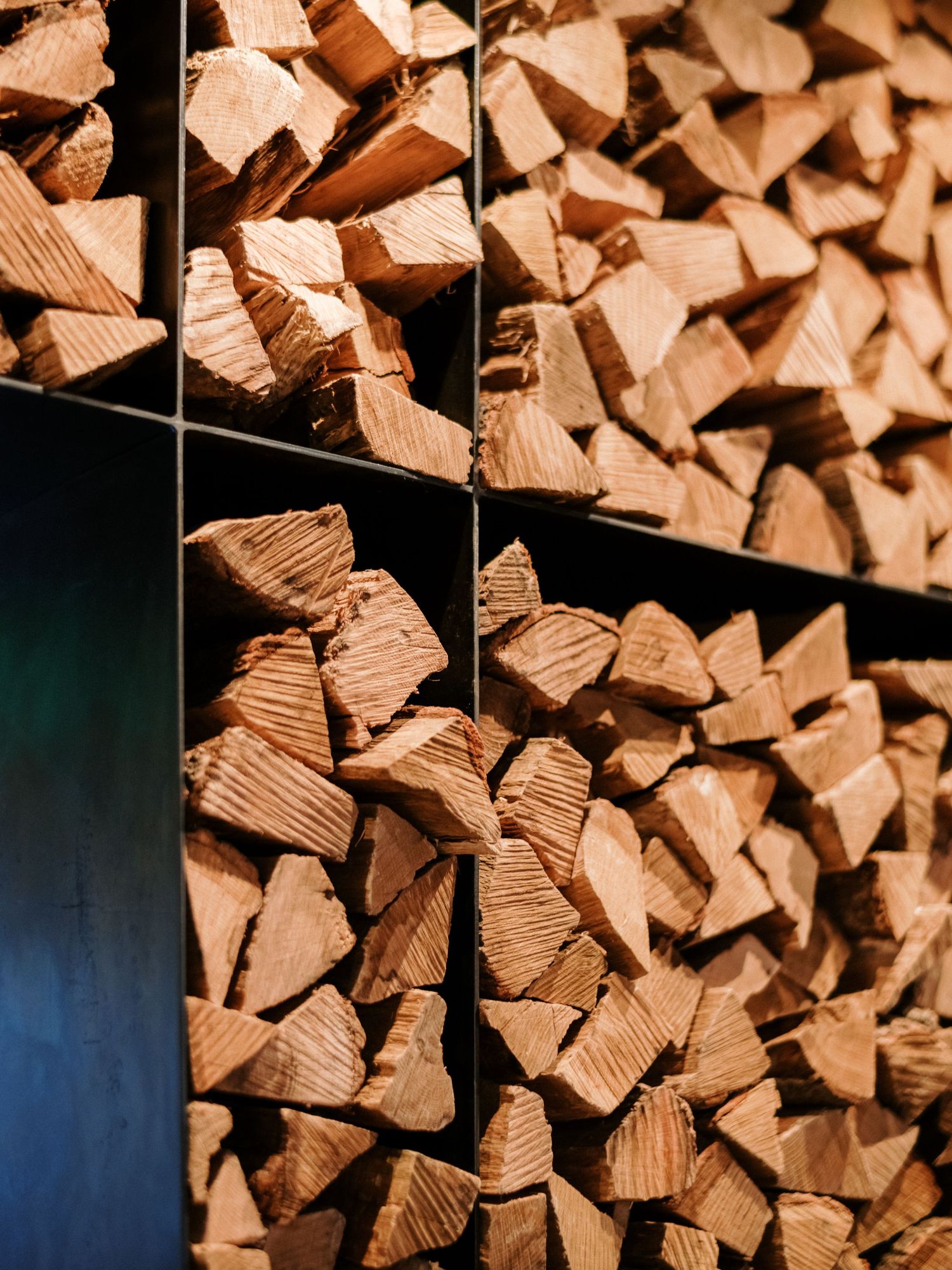 Stacked firewood arranged in geometric pattern against dark background.