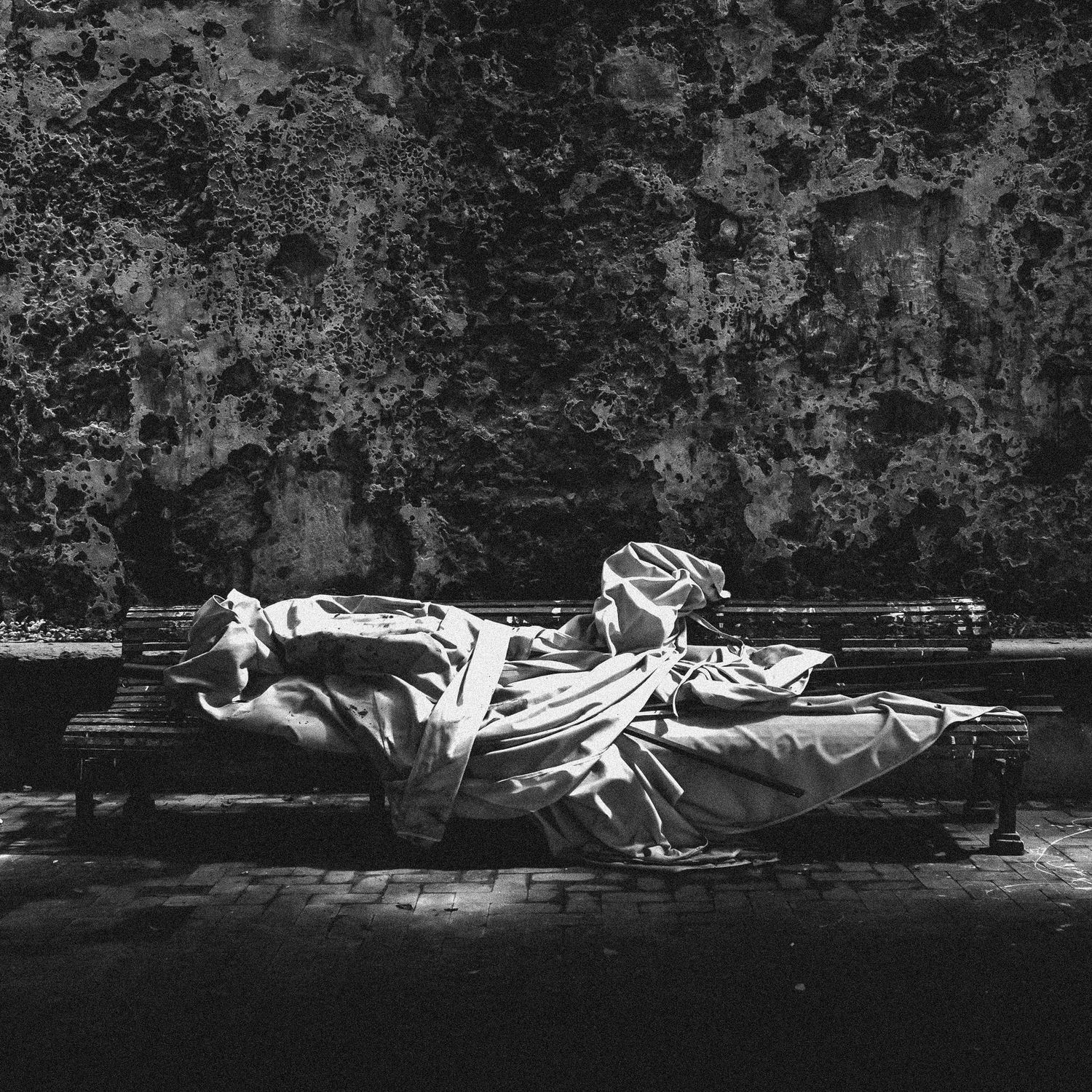 A sequence of black and white photographs showing a person lying on a bench in different resting positions.