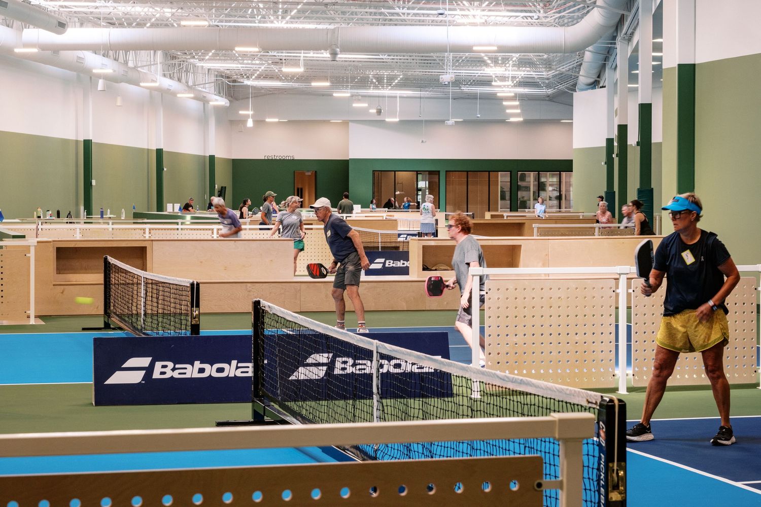 Indoor tennis courts with players practicing on professional-grade surfaces.