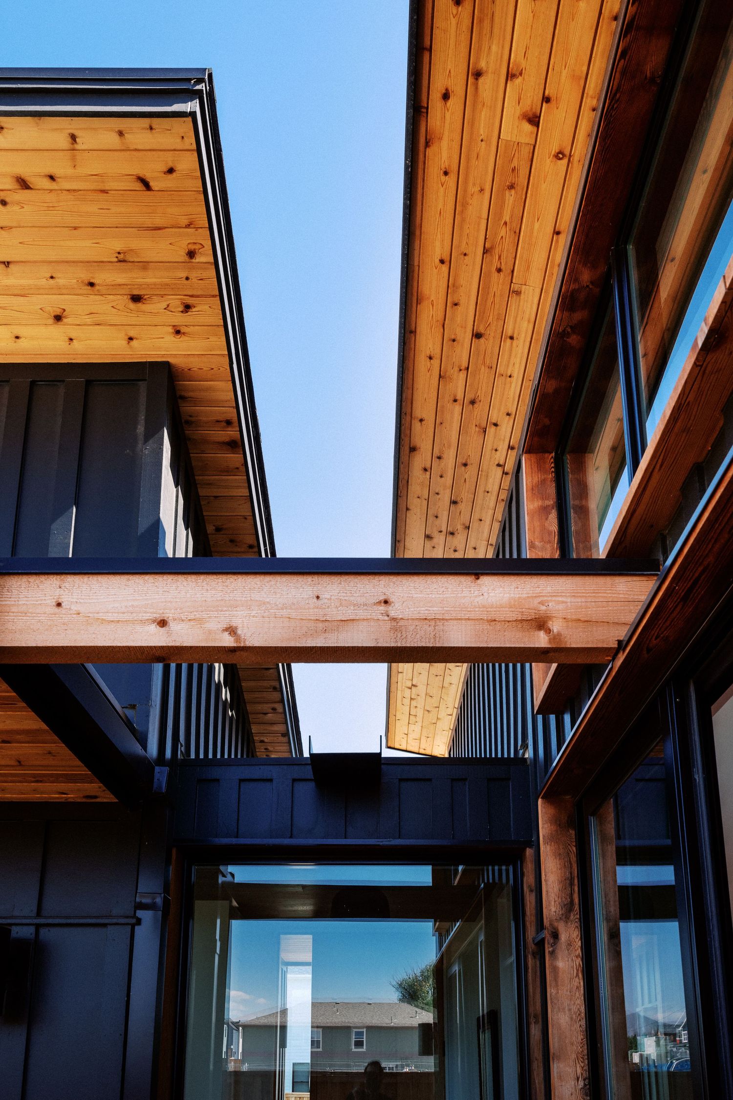 Modern wooden beam ceiling with black metal frames and large windows creating an architectural pattern.