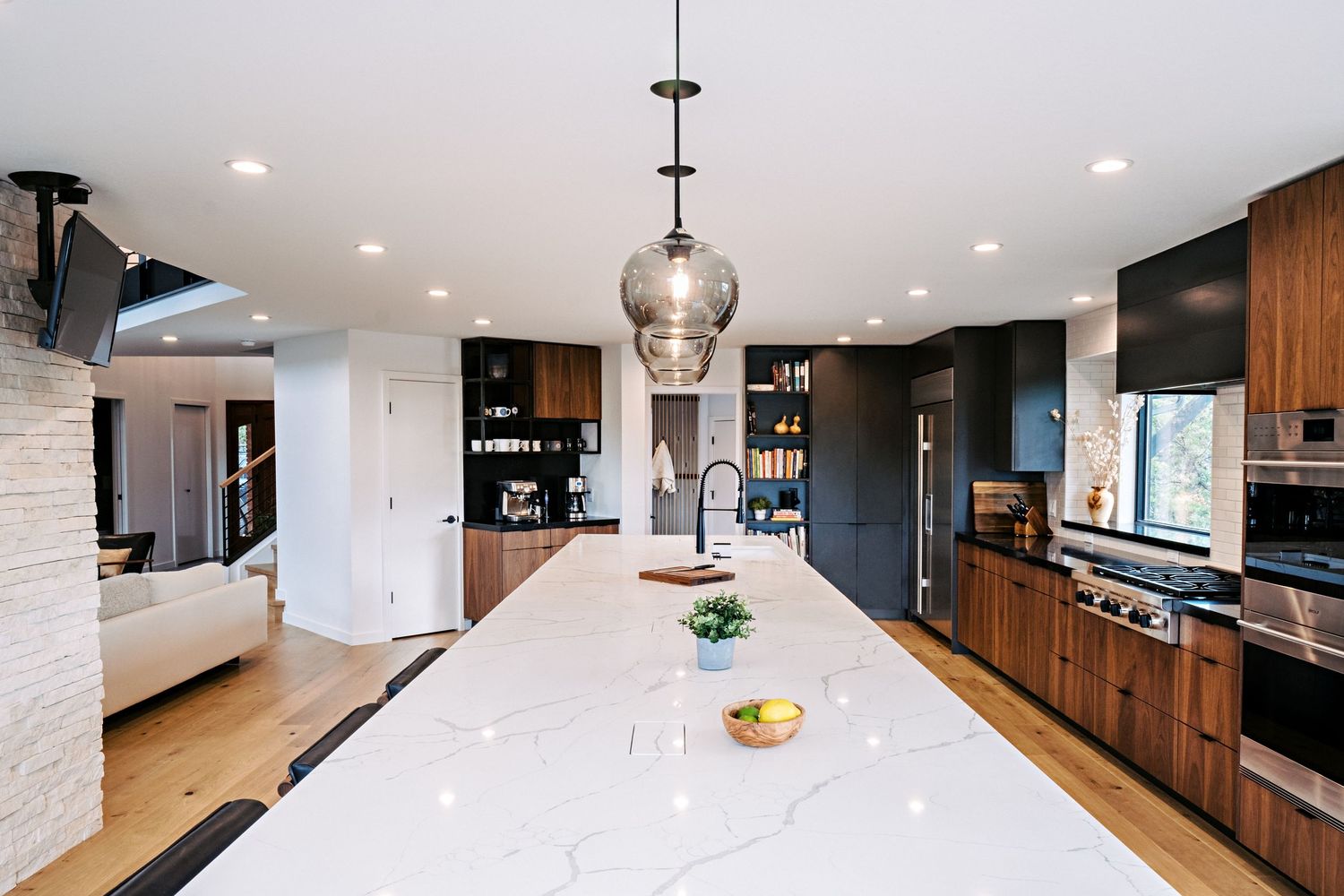 Modern kitchen with white countertops and dark wood cabinetry in an open floor plan design.