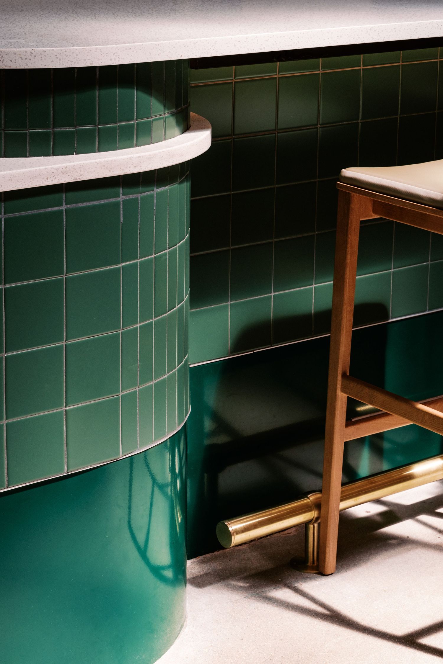 Modern interior featuring green tiled curved wall and wooden furniture in dramatic lighting.