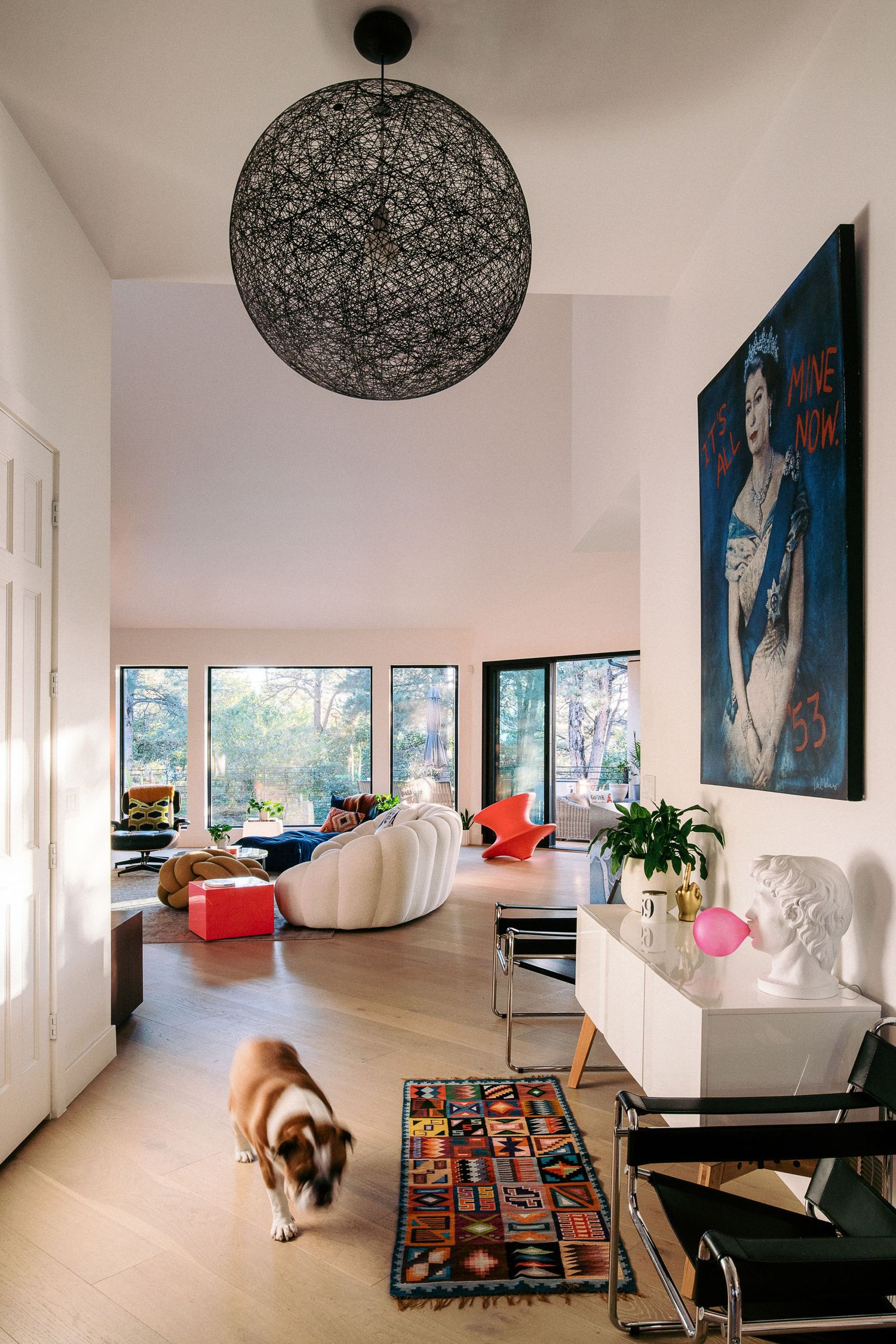 Modern living room interior with colorful rug and black pendant lamp.