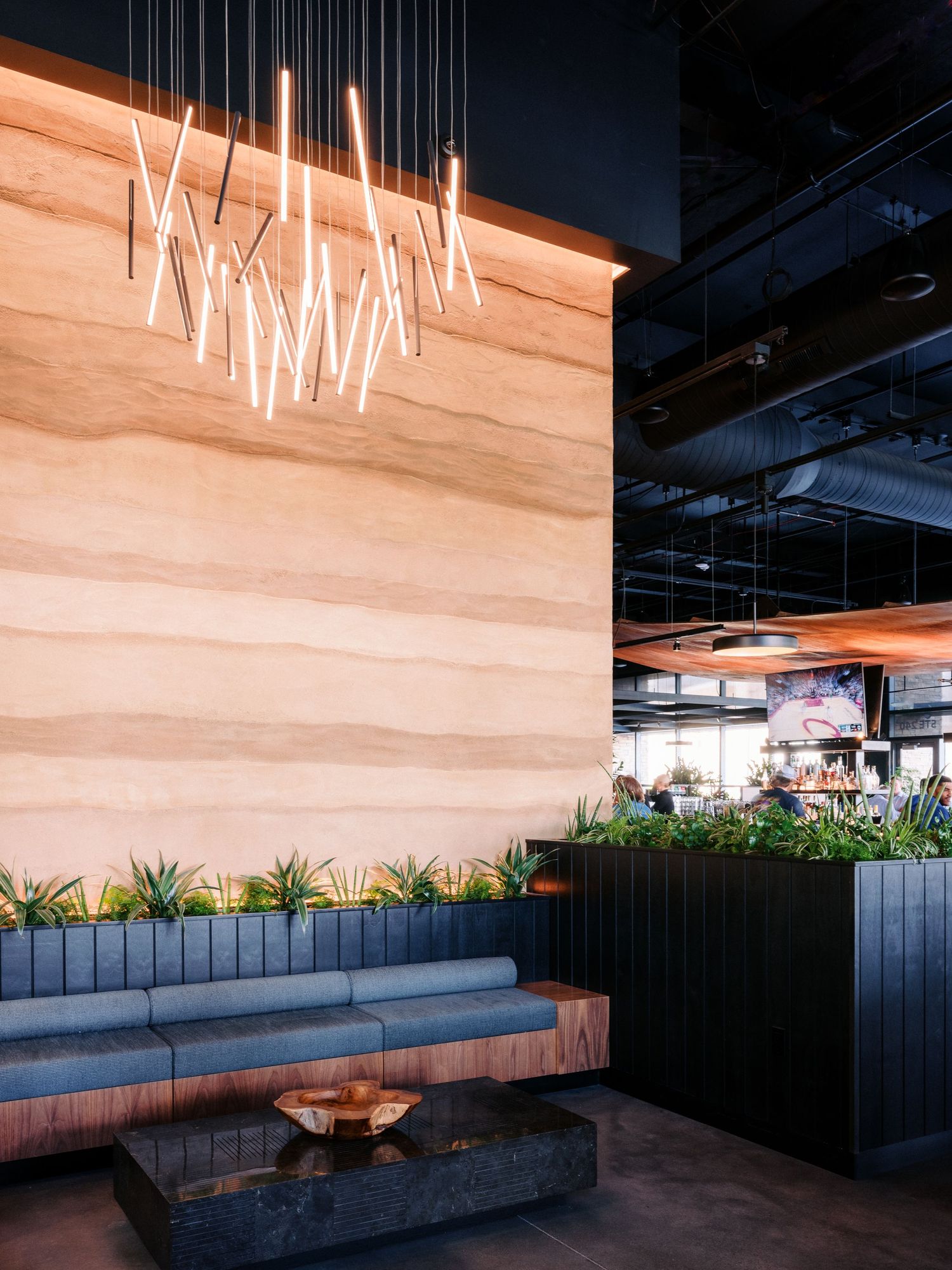 Contemporary outdoor seating area with hanging light fixtures and planters along the wall.