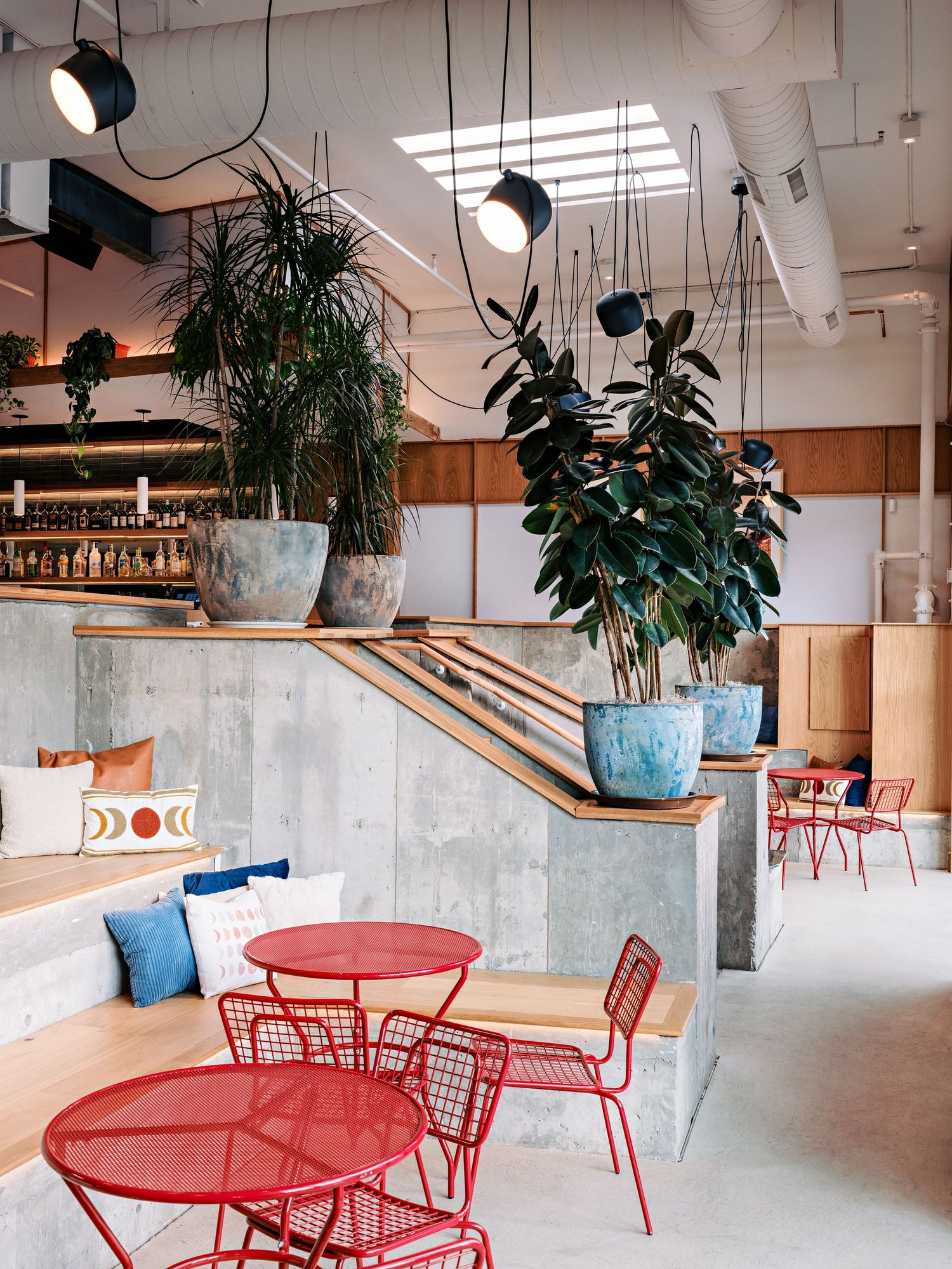 Spacious dining area featuring red metal outdoor furniture, concrete elements, and abundant natural light.