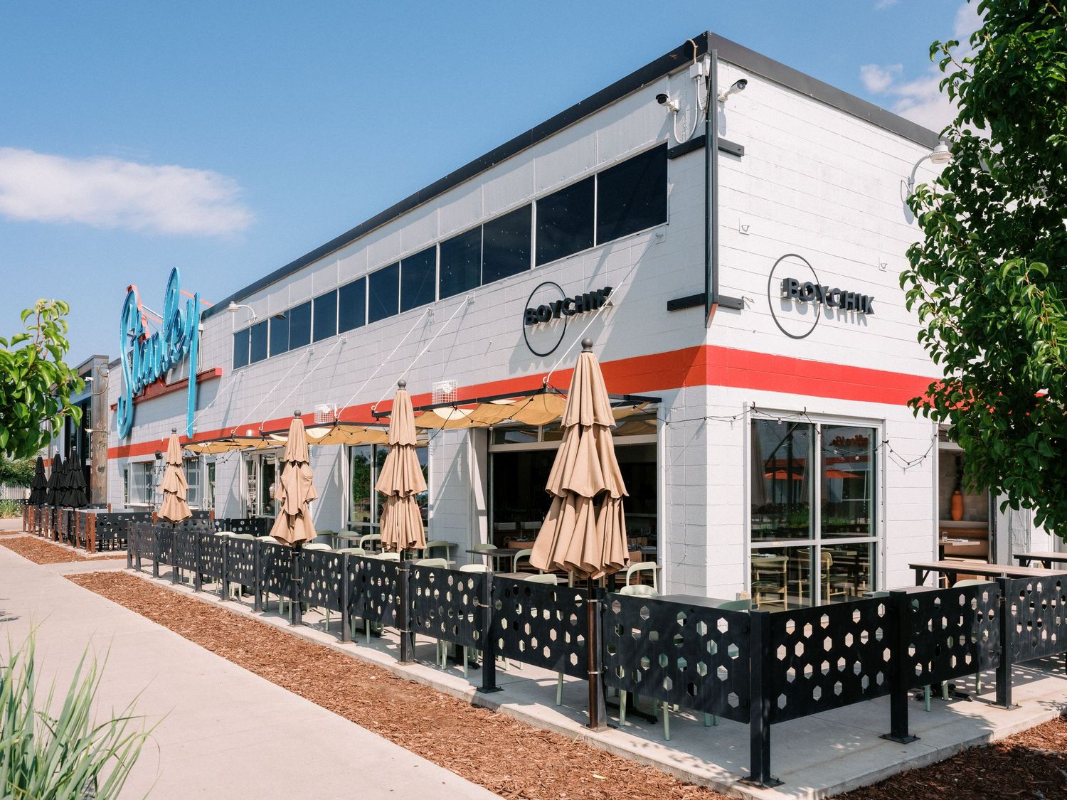 Exterior view of modern commercial building with outdoor seating and umbrellas.