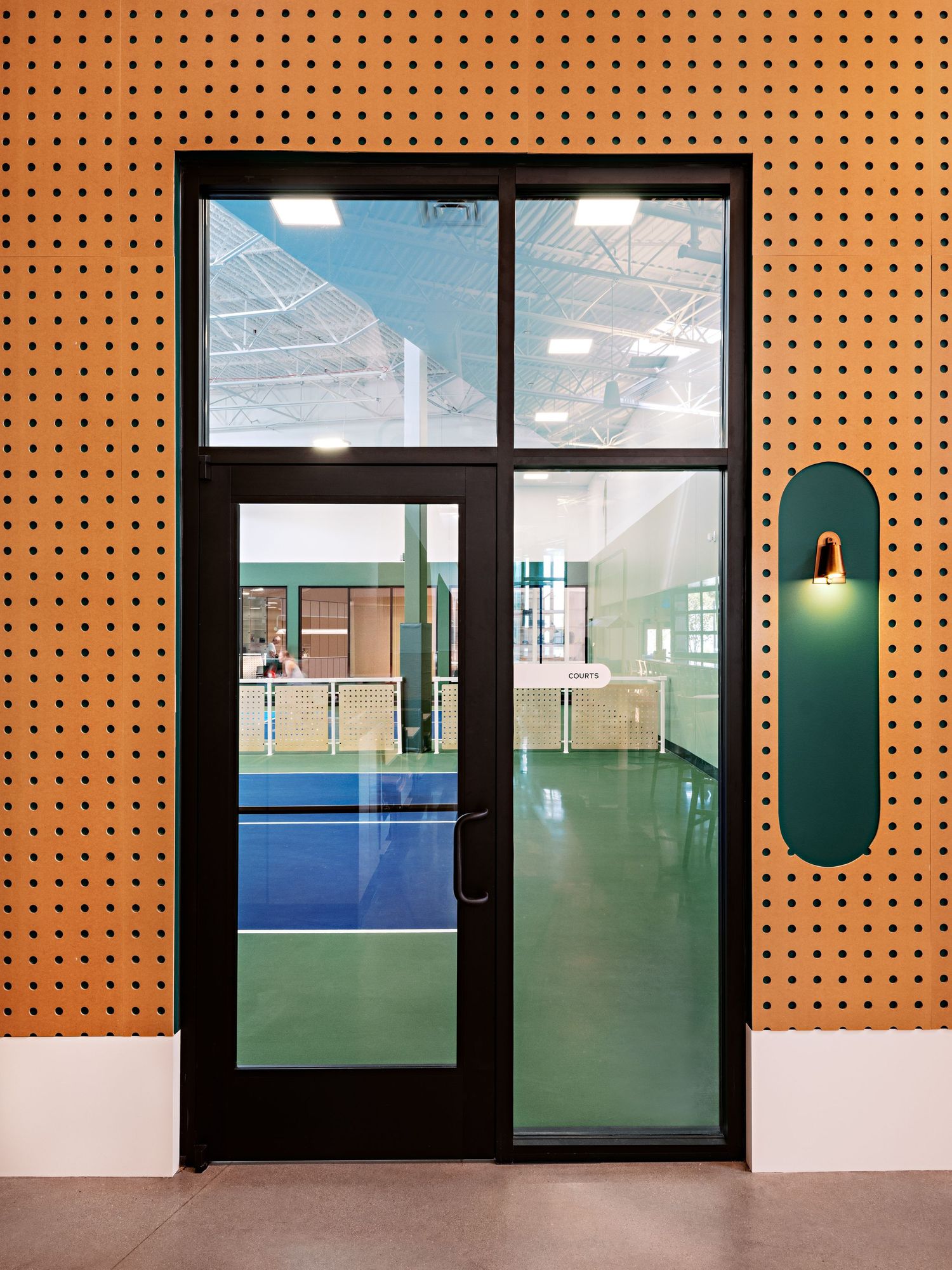 Modern interior design featuring orange perforated walls and glass doors in a sleek commercial space.