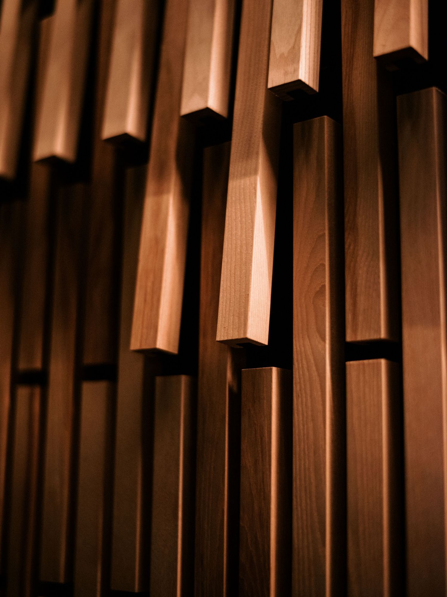 Close-up of vertical wooden slats creating geometric patterns under warm lighting.