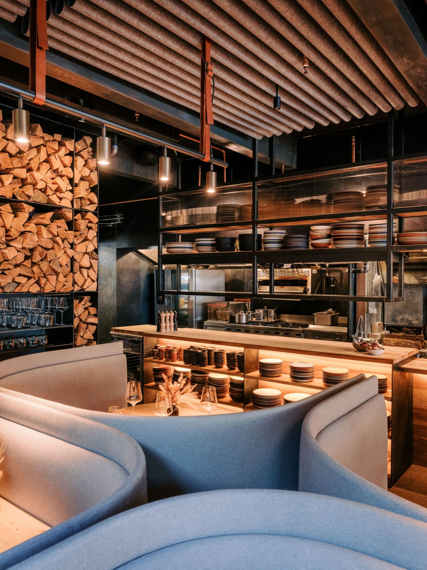Upscale restaurant interior with curved booth seating and wooden ceiling details.
