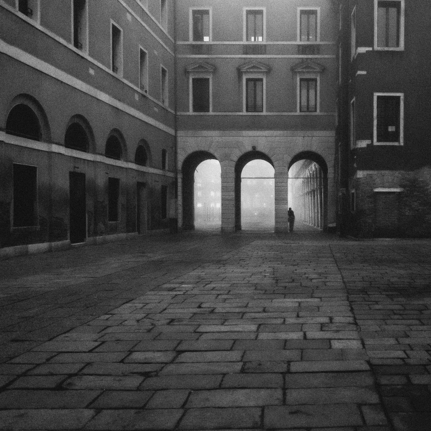 A series of black and white architectural photographs showing a cobblestone courtyard with arched passageways and buildings.