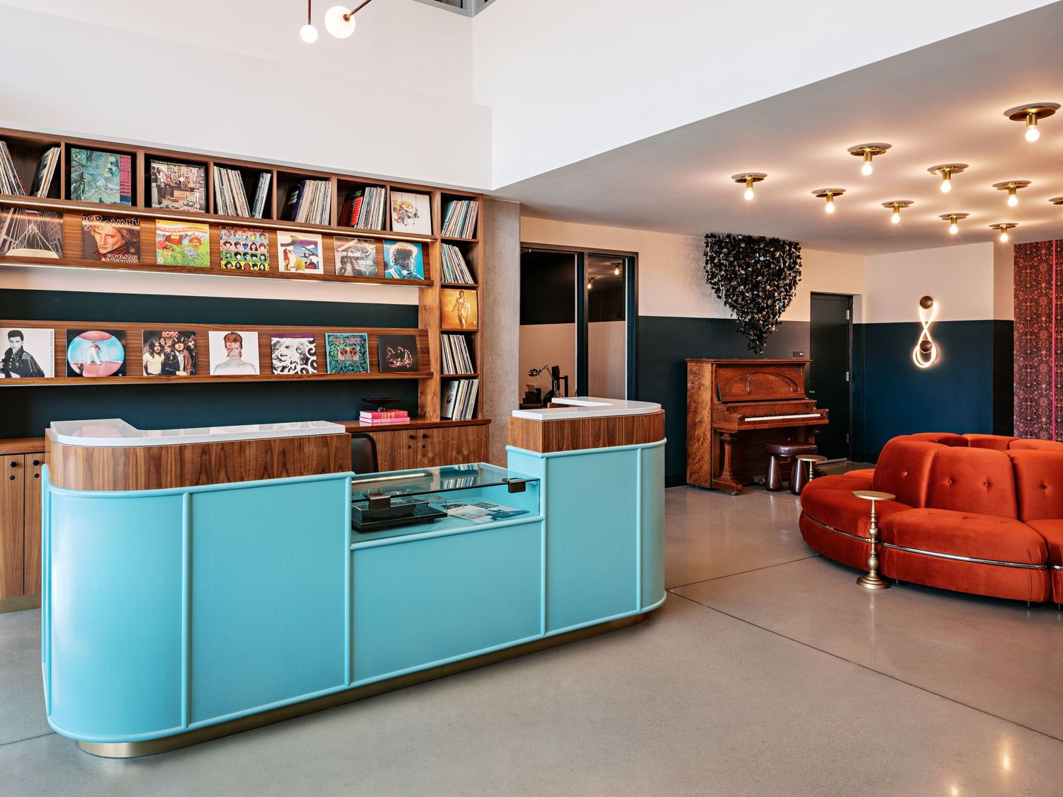 Modern library space with turquoise cabinets and orange sofa featuring built-in bookshelves.
