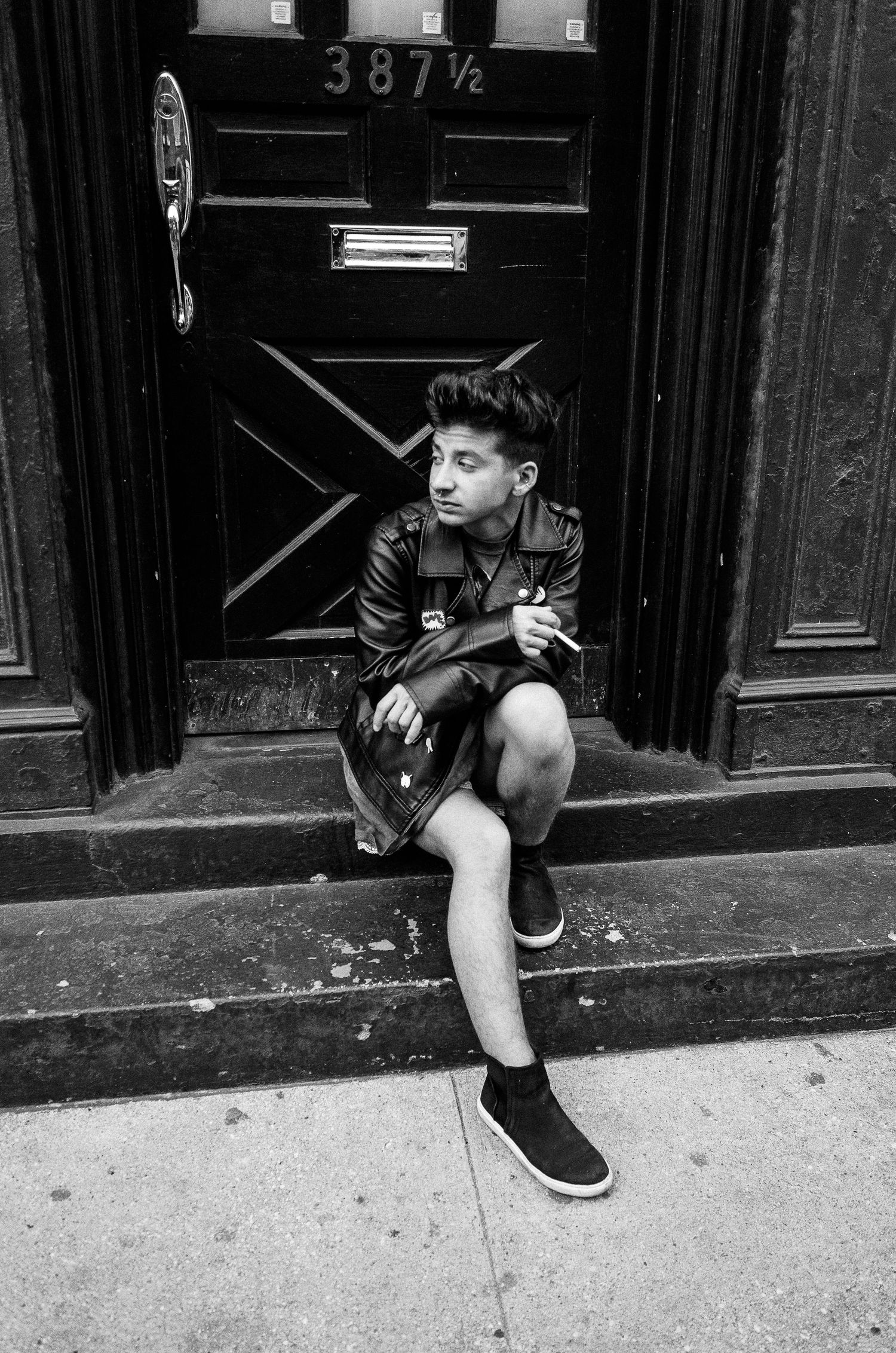 Black and white photo showing a person sitting on a doorstep in an urban setting, split into four sequential panels.