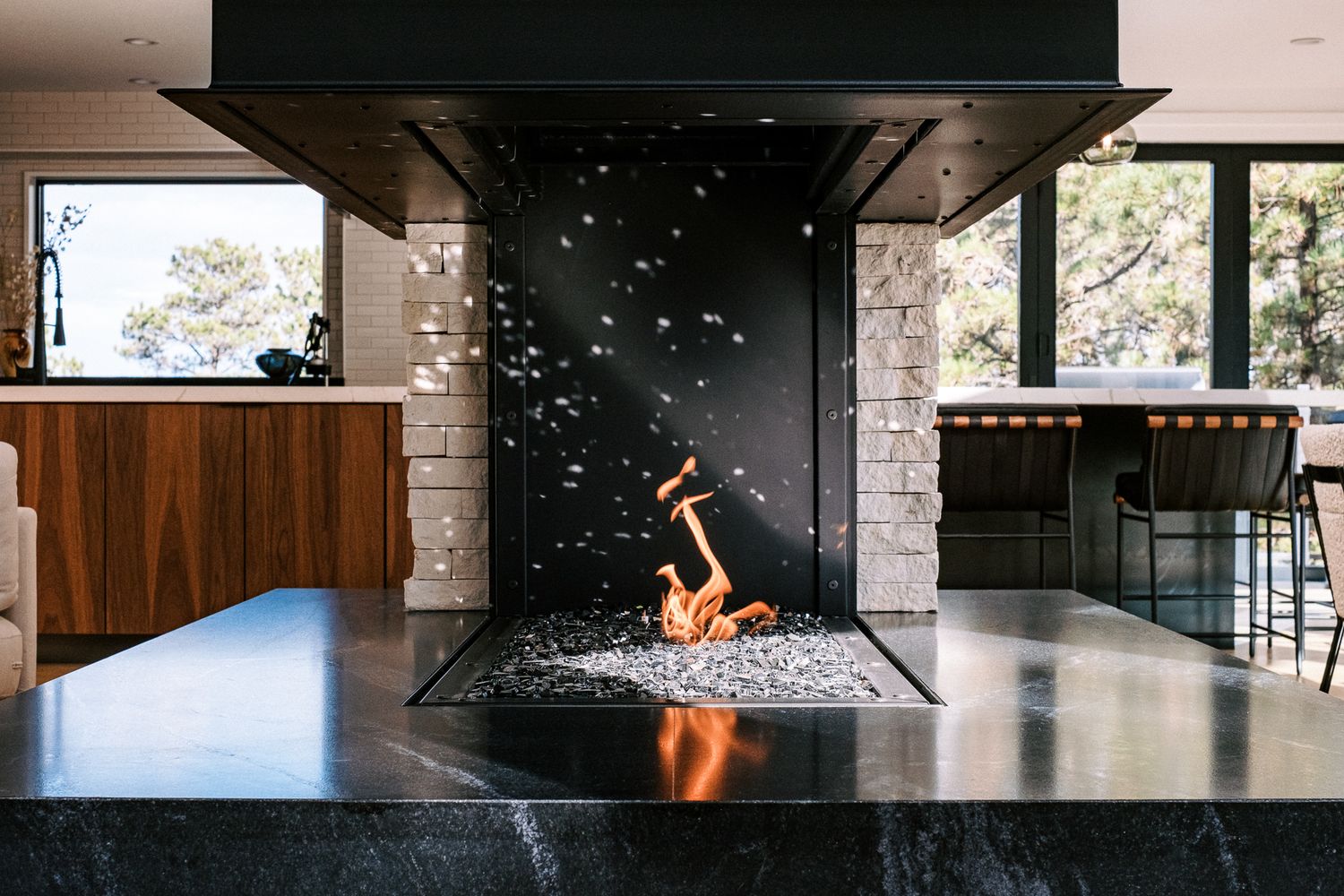 Modern mountain home exterior features sleek black metal and warm wood accents against white stone walls.