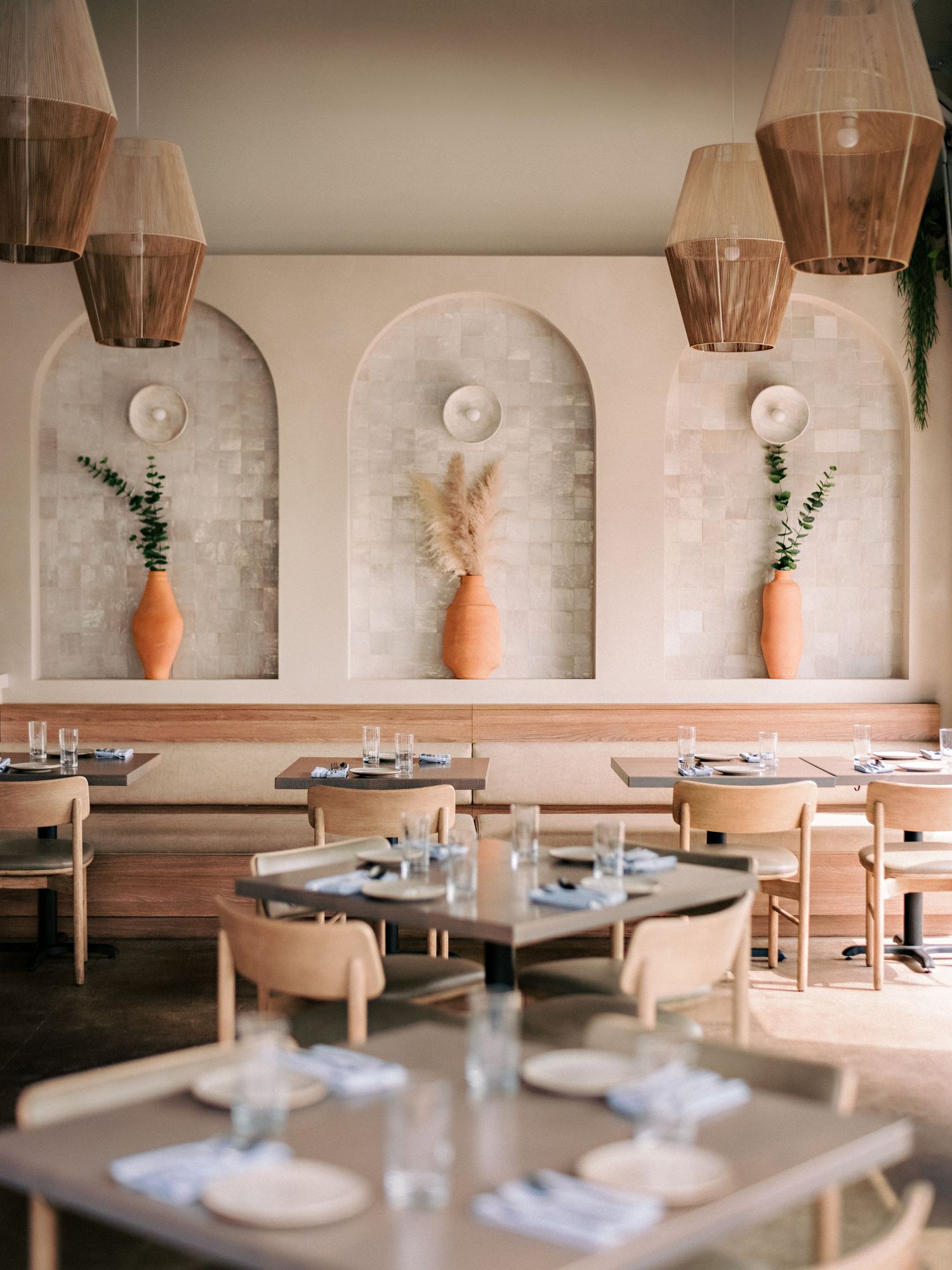 Modern dining room with wooden pendant lights and built-in wall alcoves displaying decorative vases.