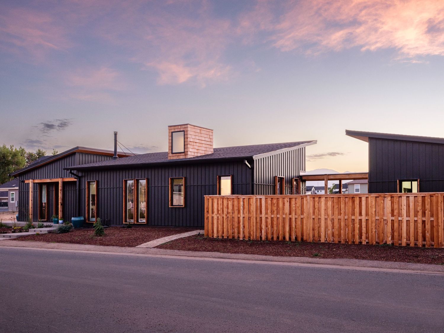 Panoramic sunset view of contemporary housing development with dramatic pink and purple sky.