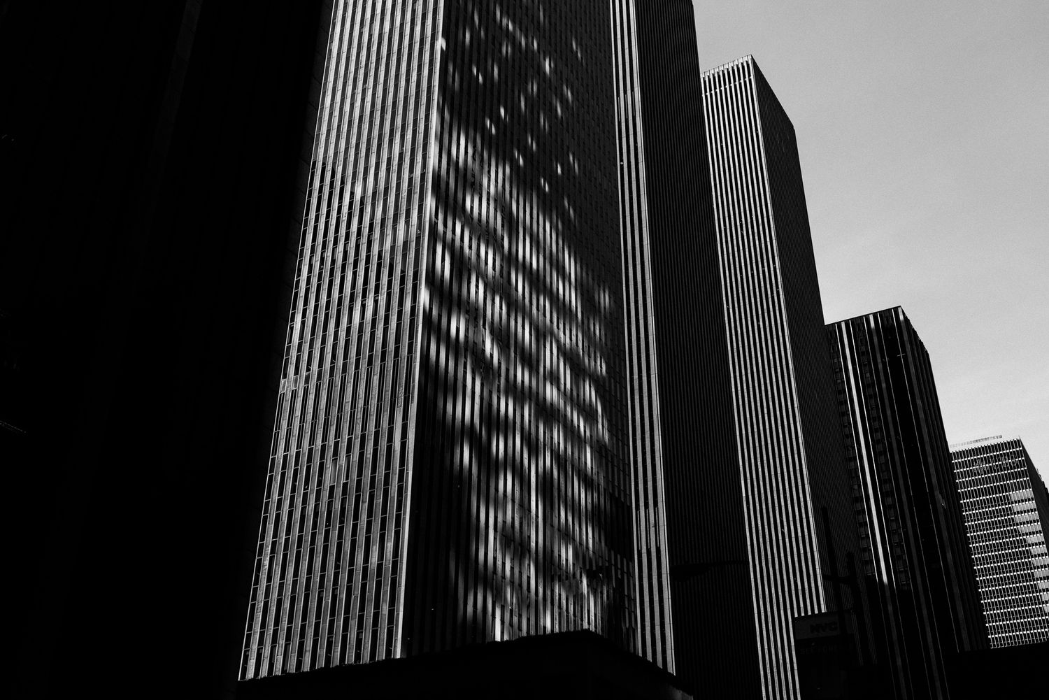 Black and white architectural photograph of modern skyscraper facades creating geometric patterns.