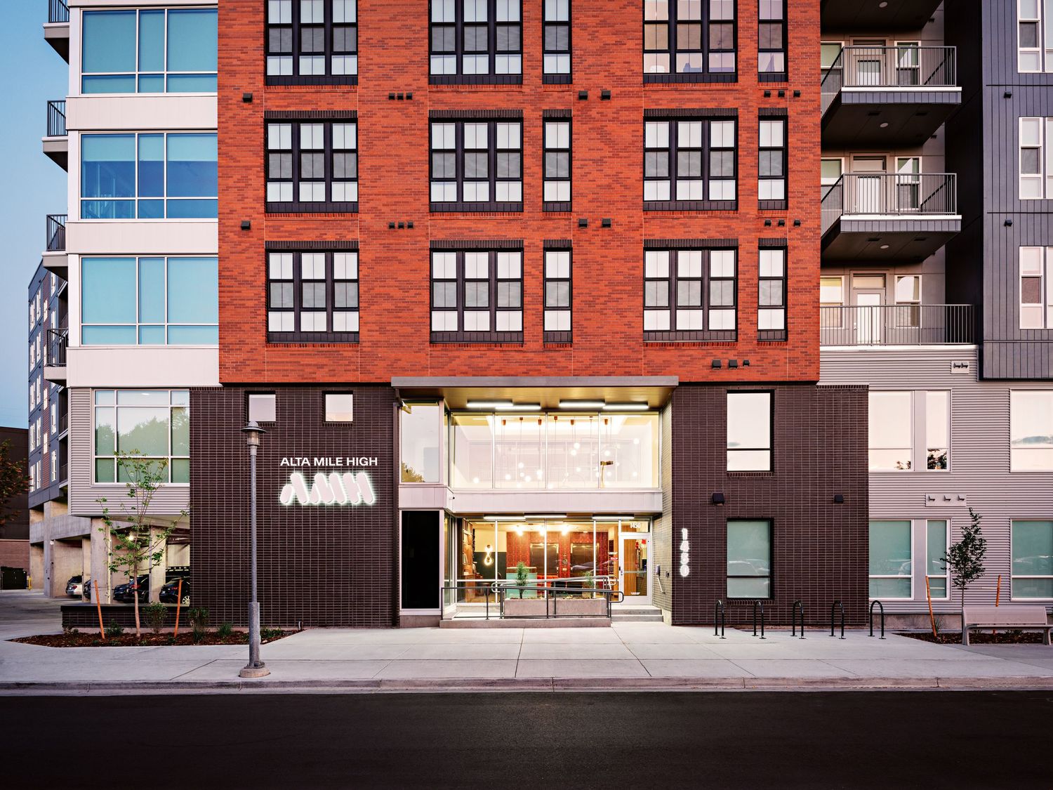 Contemporary apartment building exterior with red brick facade and black trim details.