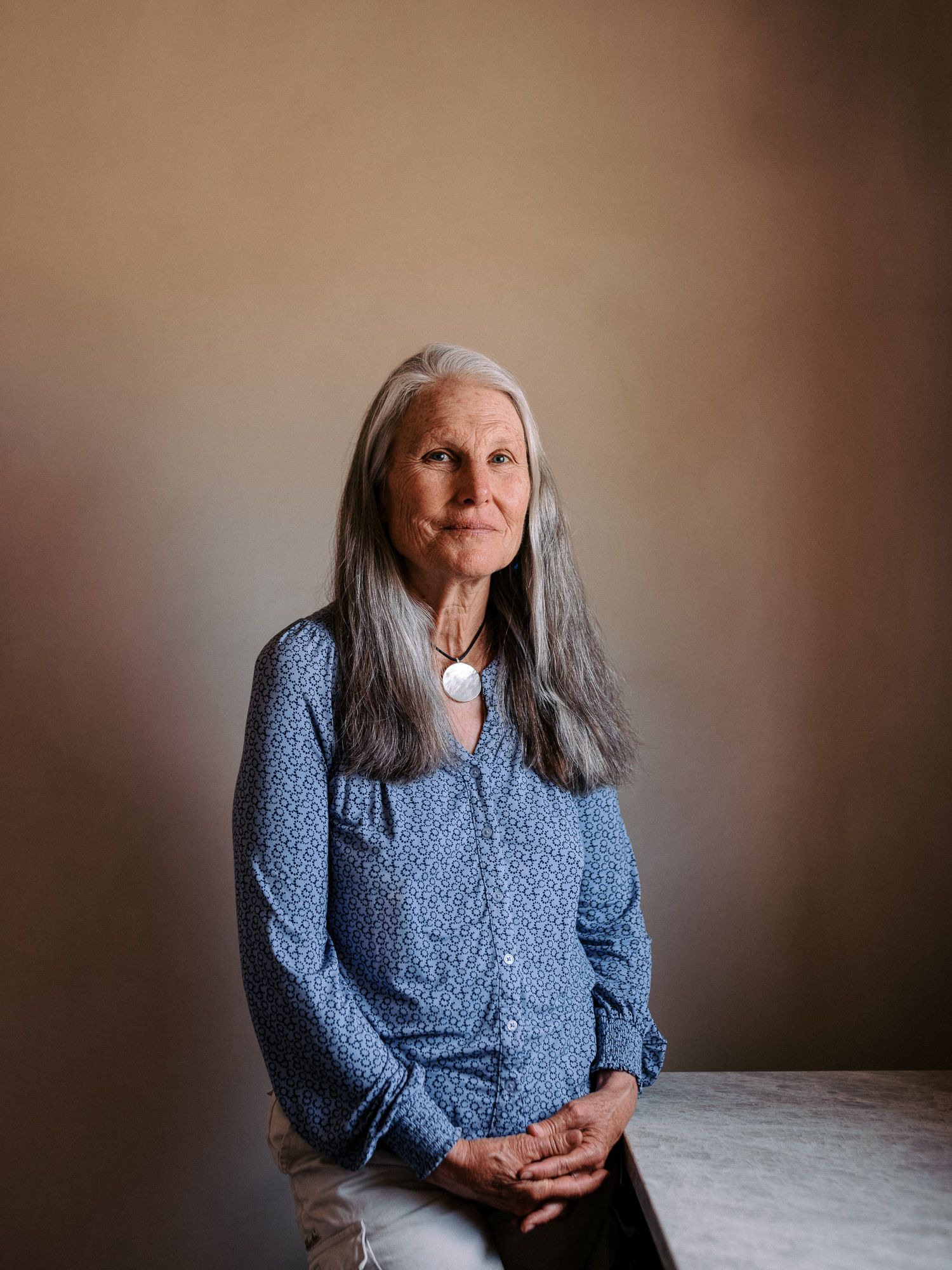 Person in blue sweater sitting thoughtfully against neutral background.