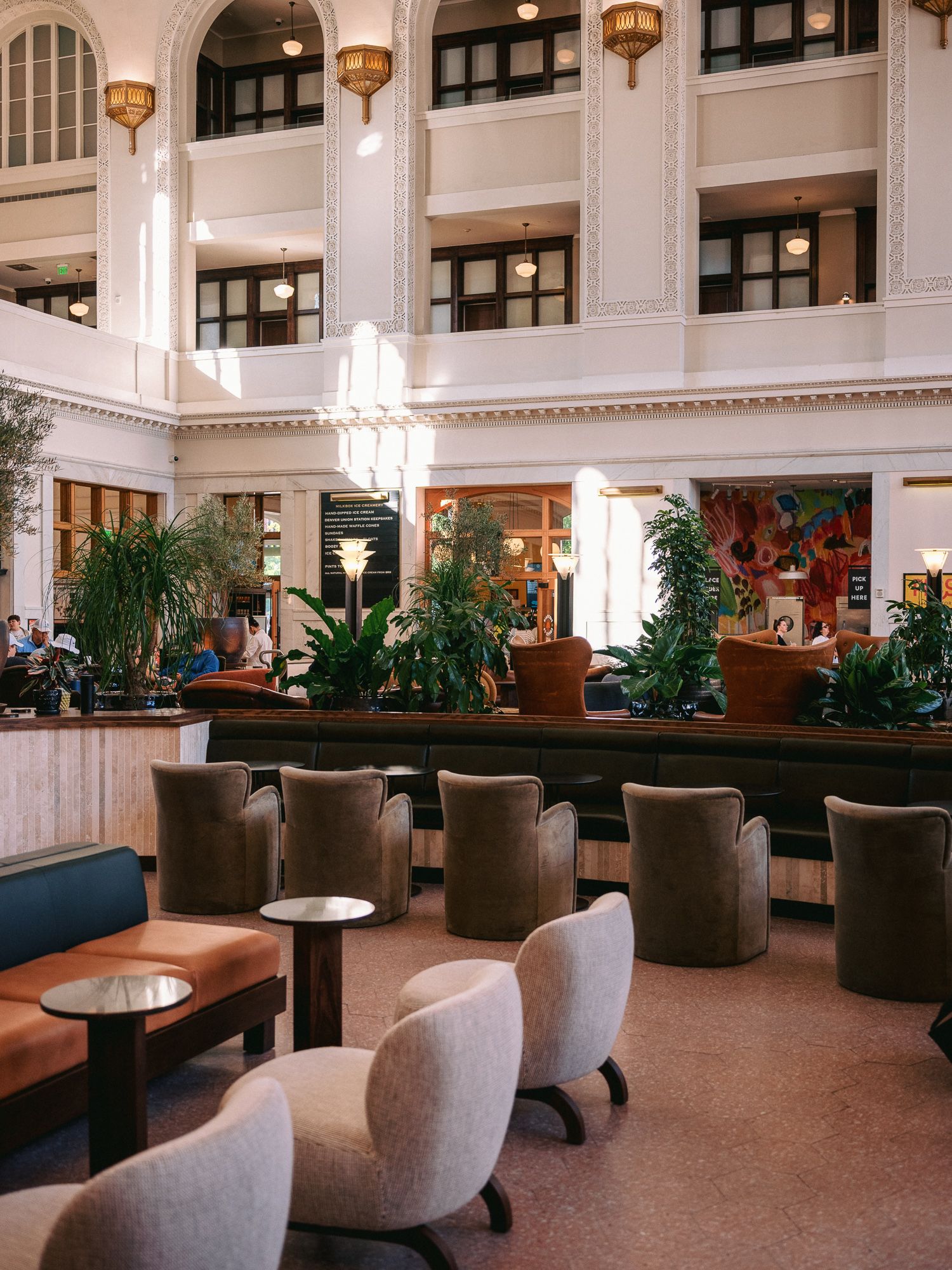 Elegant hotel lobby lounge with plush seating, hanging lamps, and indoor plants.
