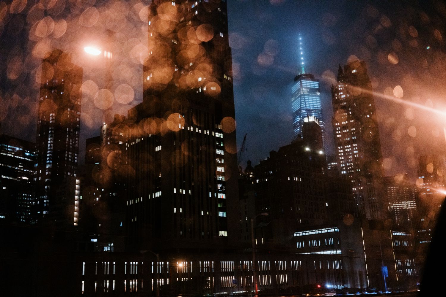 Moody nighttime cityscape with illuminated buildings and fog creating atmospheric scene.