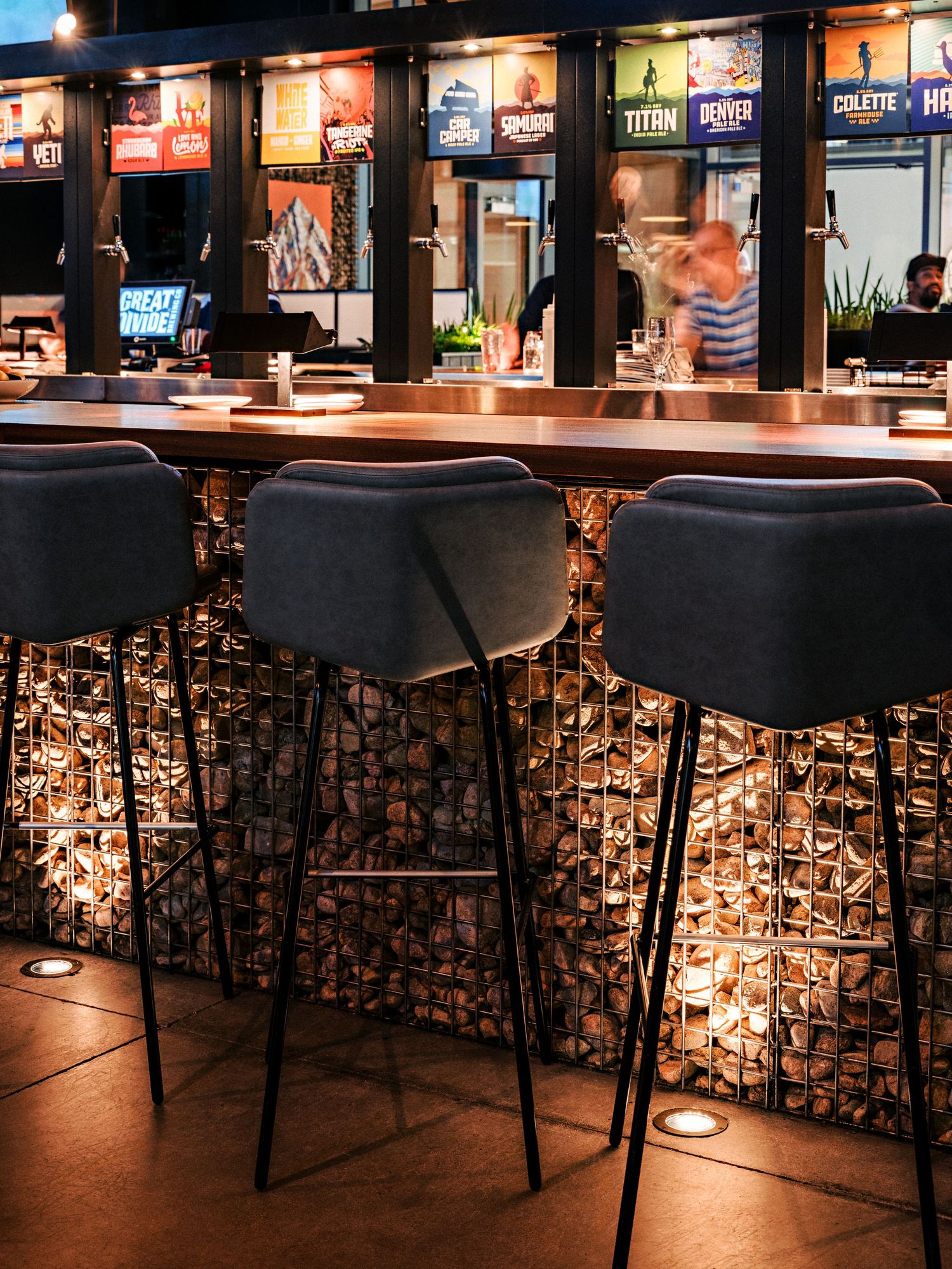 Bar counter with decorative illuminated base panels and modern black bar stools.
