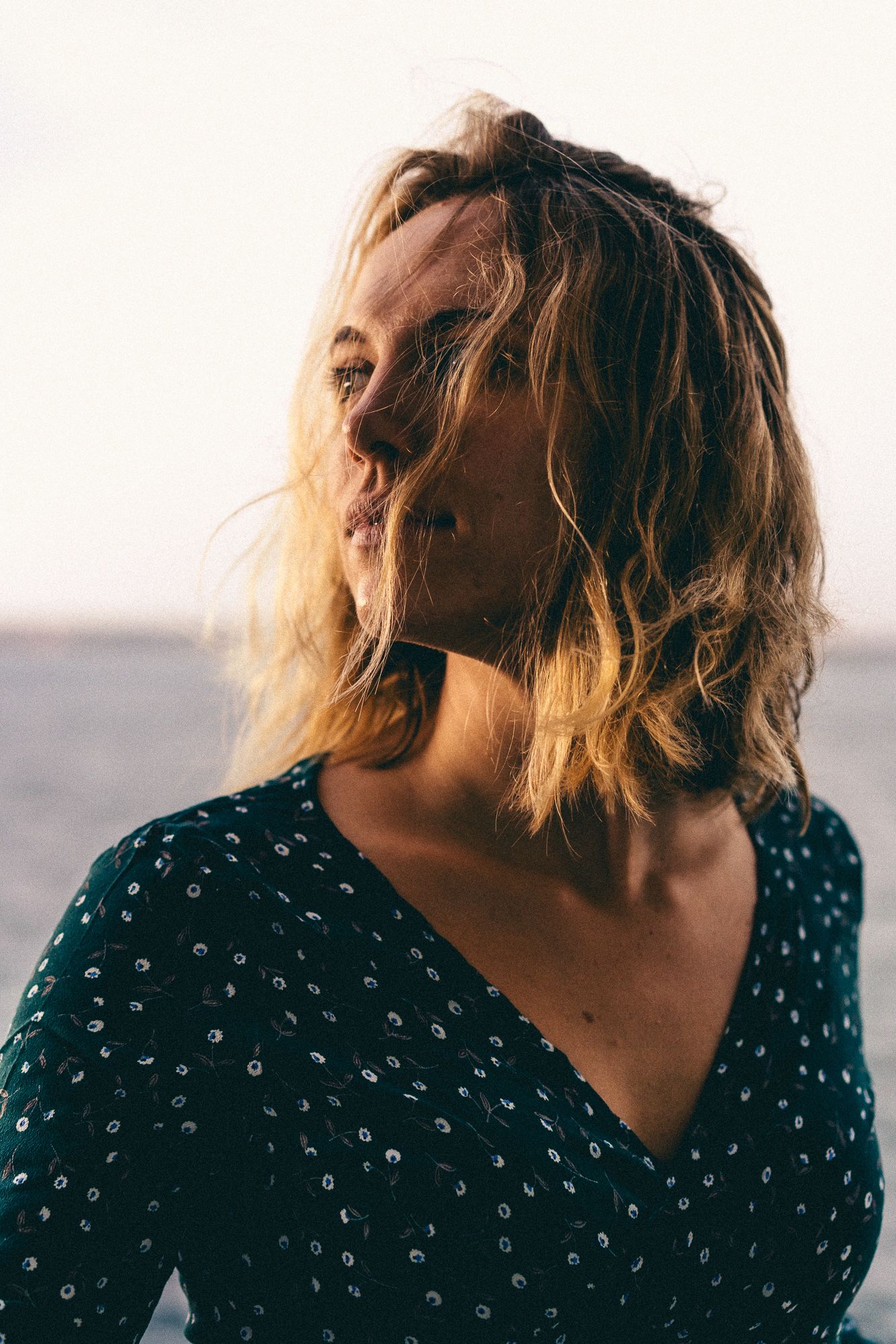 A sequence of artistic portraits showing movement with blonde hair against a bright background in a polka dot dress.