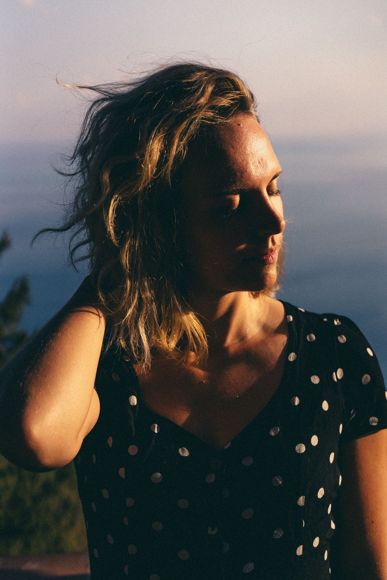 A series of silhouetted profile shots at sunset showing someone in a polka dot dress with windswept hair.