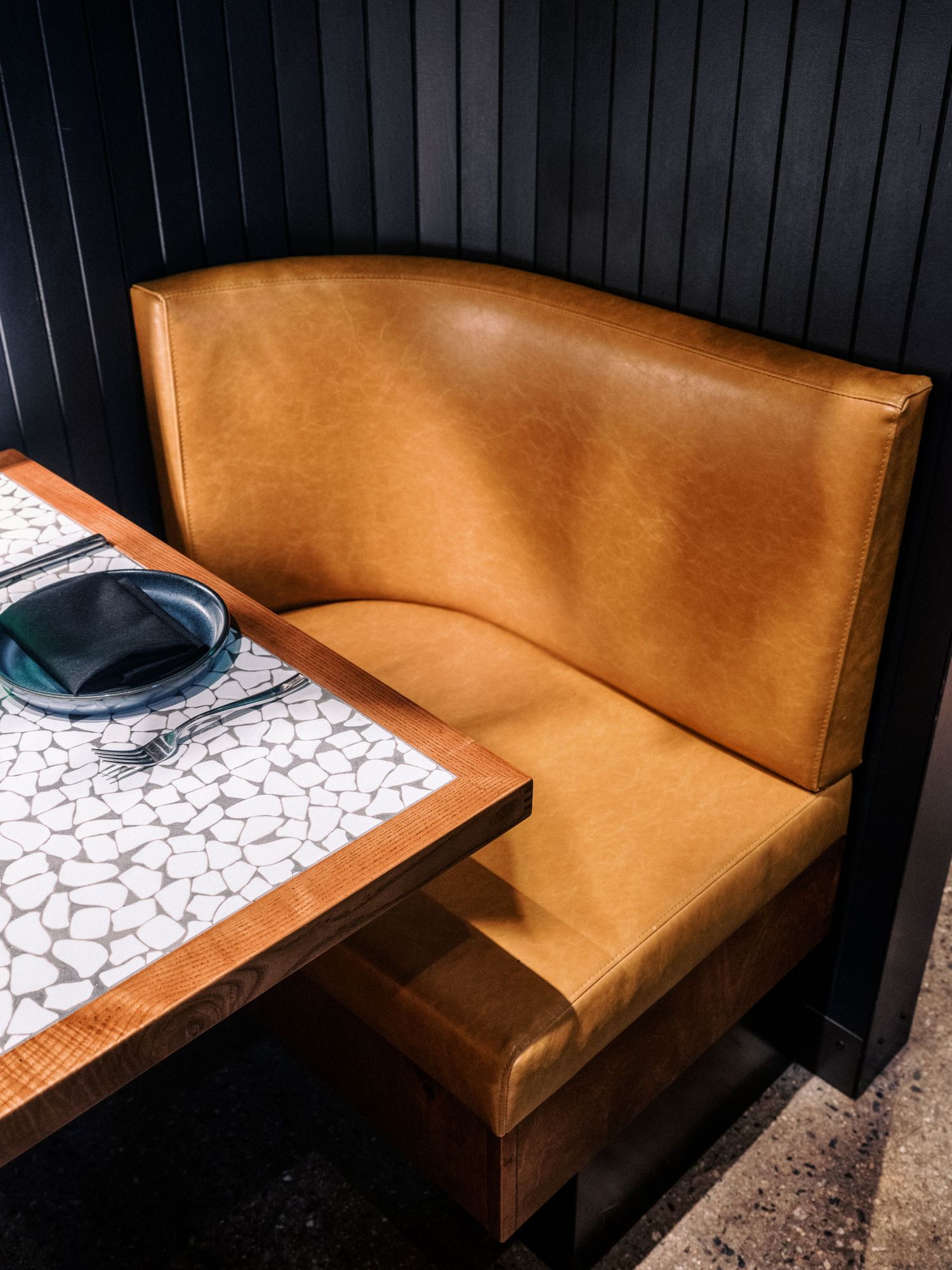 Modern restaurant booth with tan leather seating and geometric pattern table.