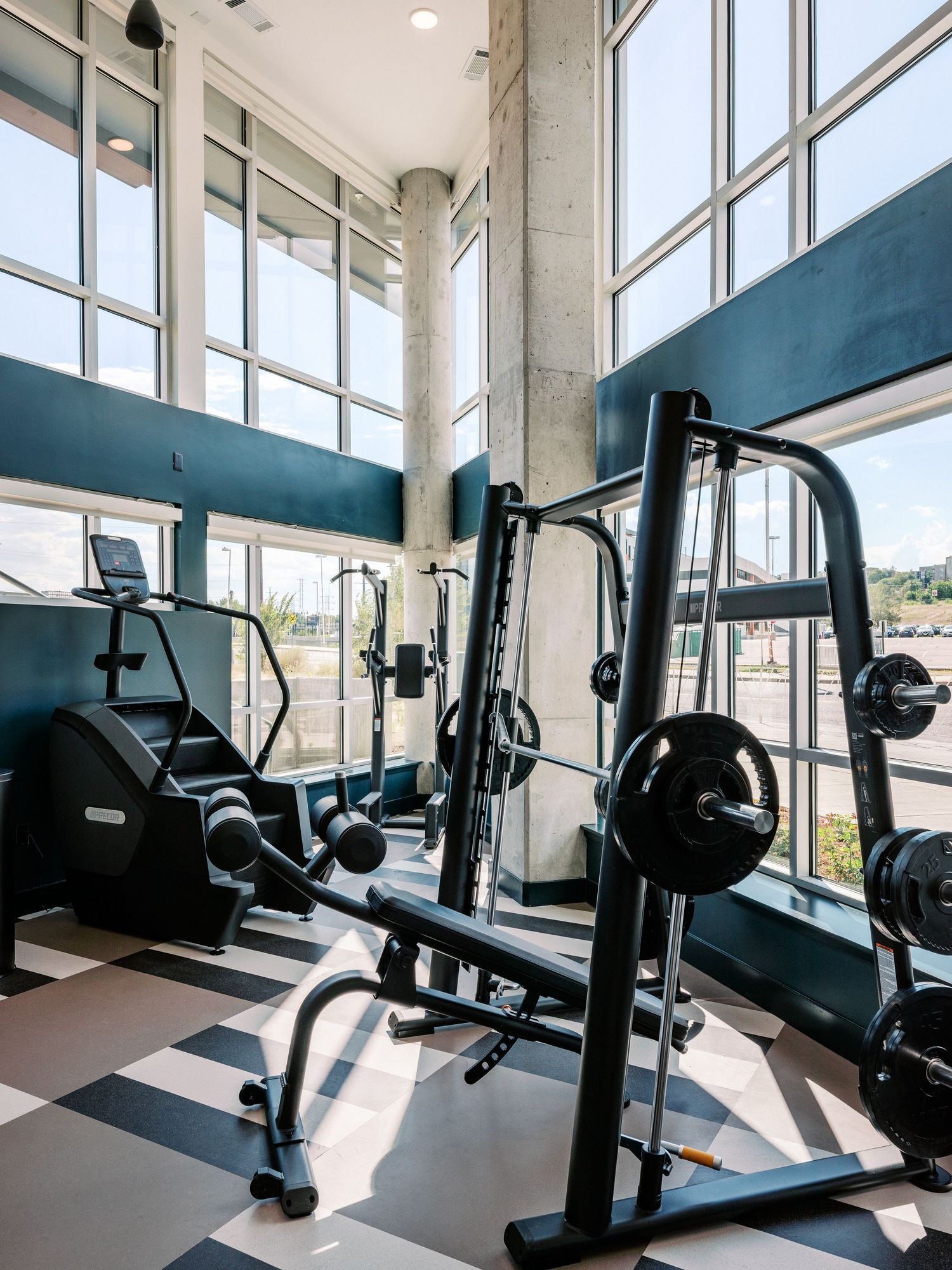 Well-equipped gym facility featuring weight machines and cardio equipment with large windows.