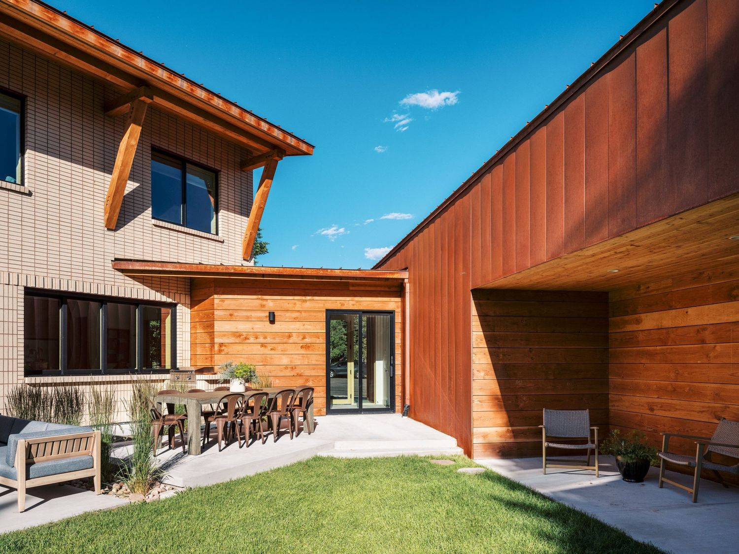Contemporary residential architecture featuring wood siding and angular rooflines against blue sky.