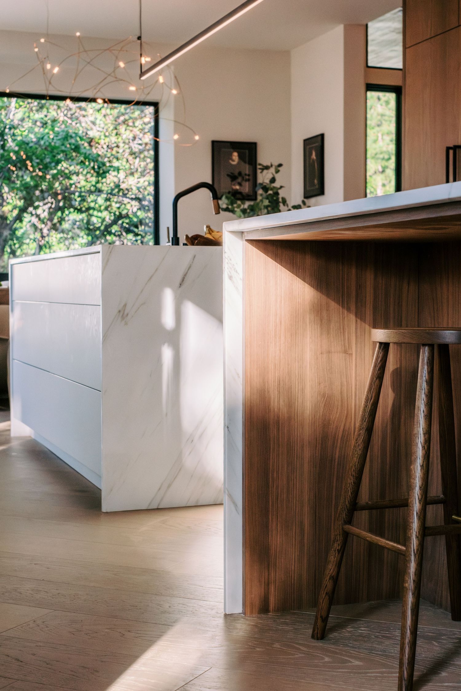 Modern kitchen island with white marble top and wooden base featuring bar seating.