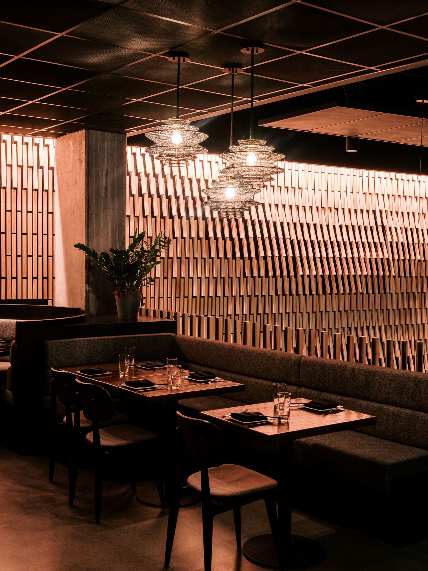 Dimly lit restaurant interior with wooden wall panels and booth seating arrangements.
