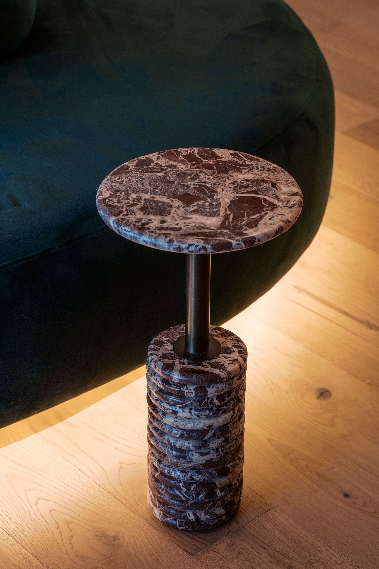 Decorative marble side table with stacked circular base on wooden flooring.