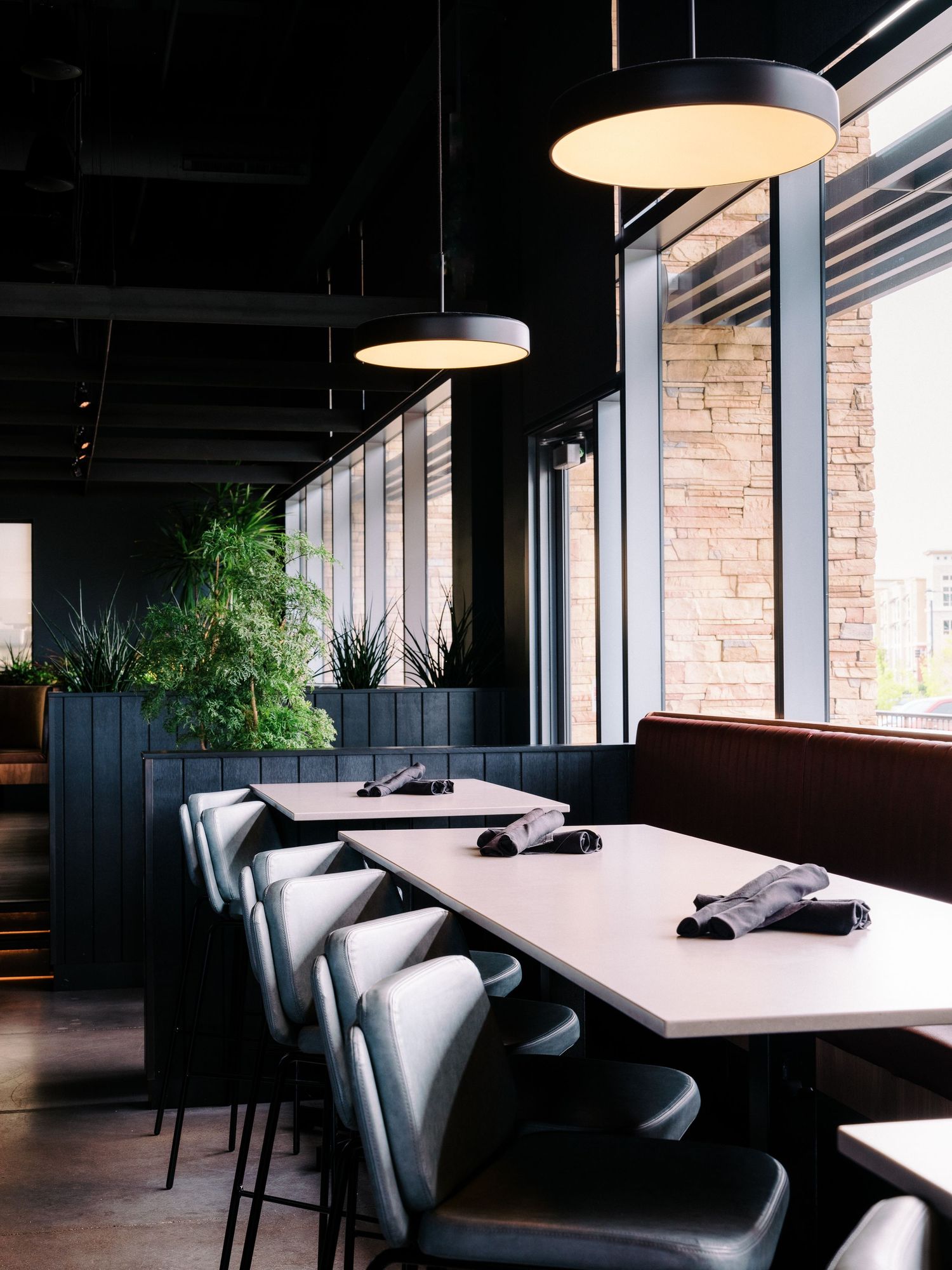 Modern restaurant interior with white tables, gray chairs, and pendant lighting creates an elegant dining atmosphere.