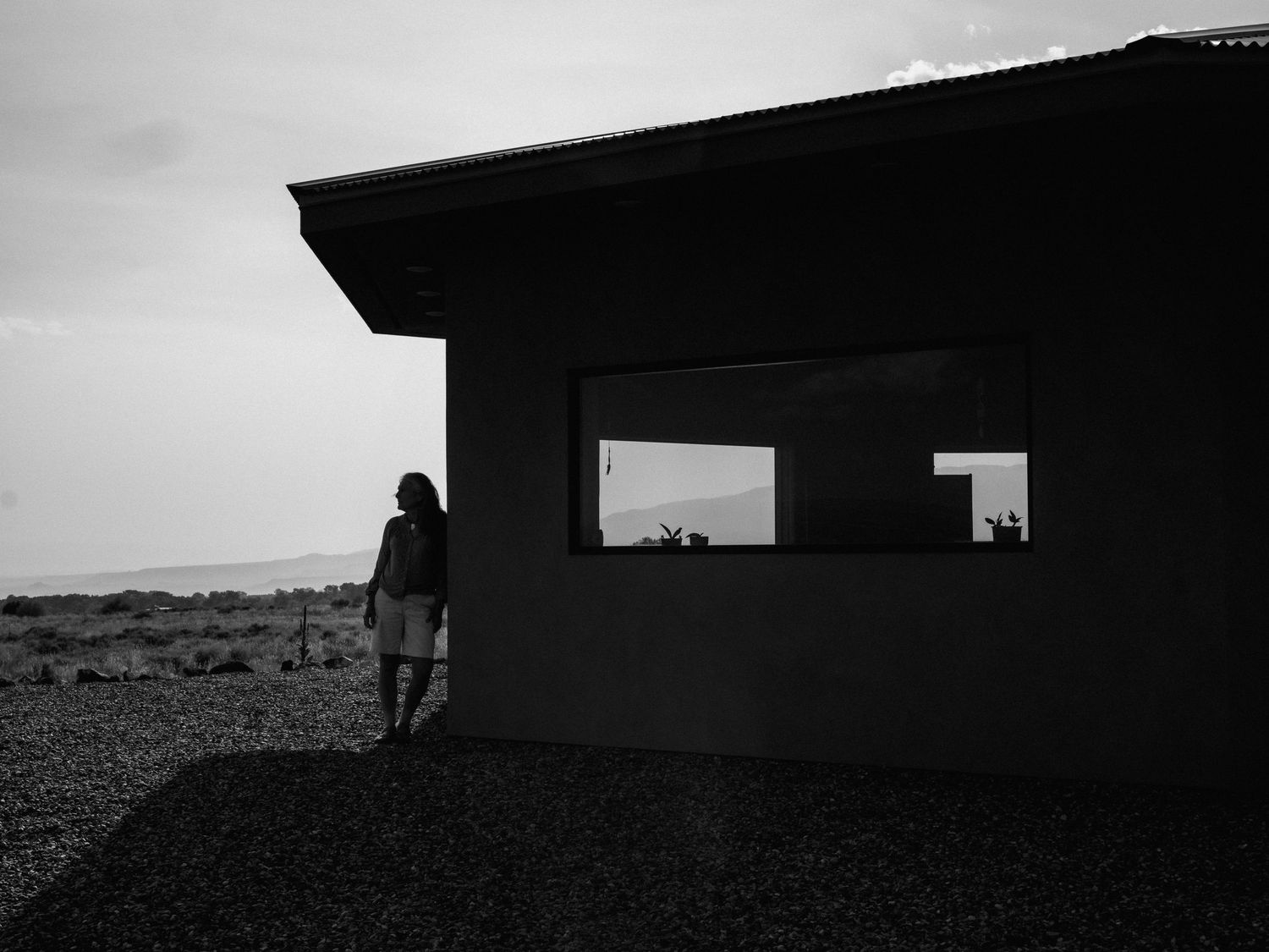 Black and white architectural photo of building with rectangular windows overlooking landscape.