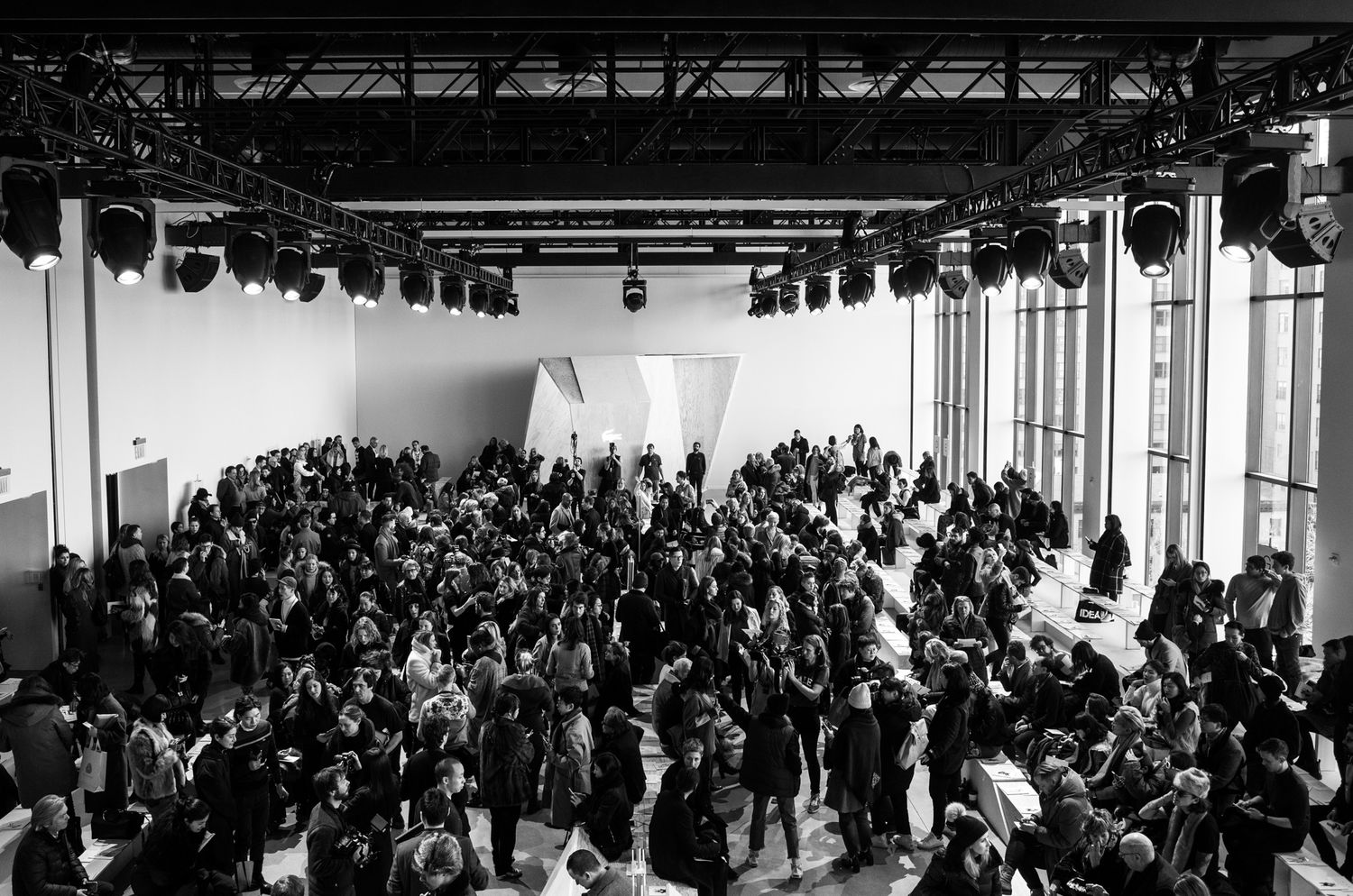 Large crowd gathers in a modern white exhibition hall with high ceilings and industrial lighting.
