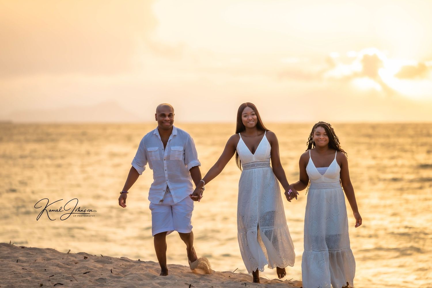 Family walking hand in hand on beach during golden hour sunset.