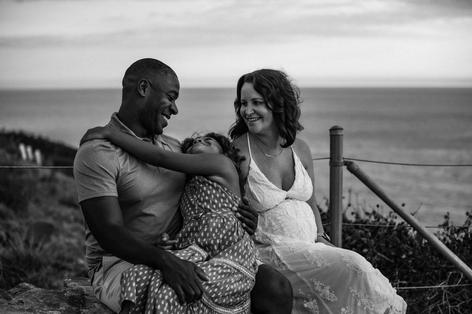 Couple shares intimate black and white moment on coastal overlook.