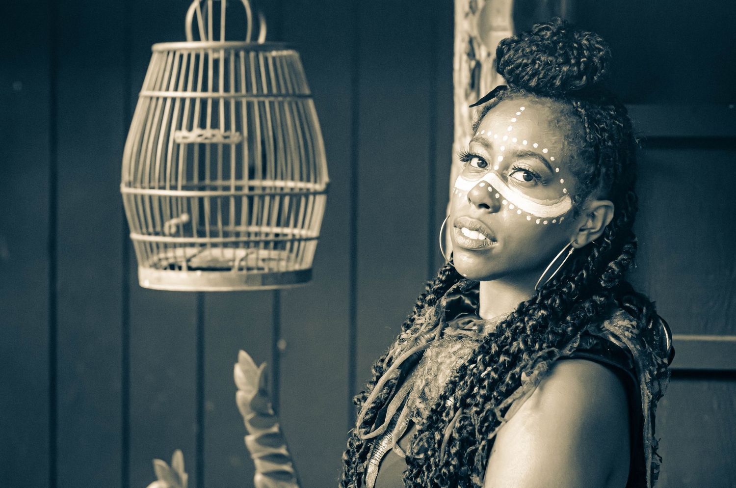 Dramatic portrait series with decorative birdcage lighting elements in dark setting.