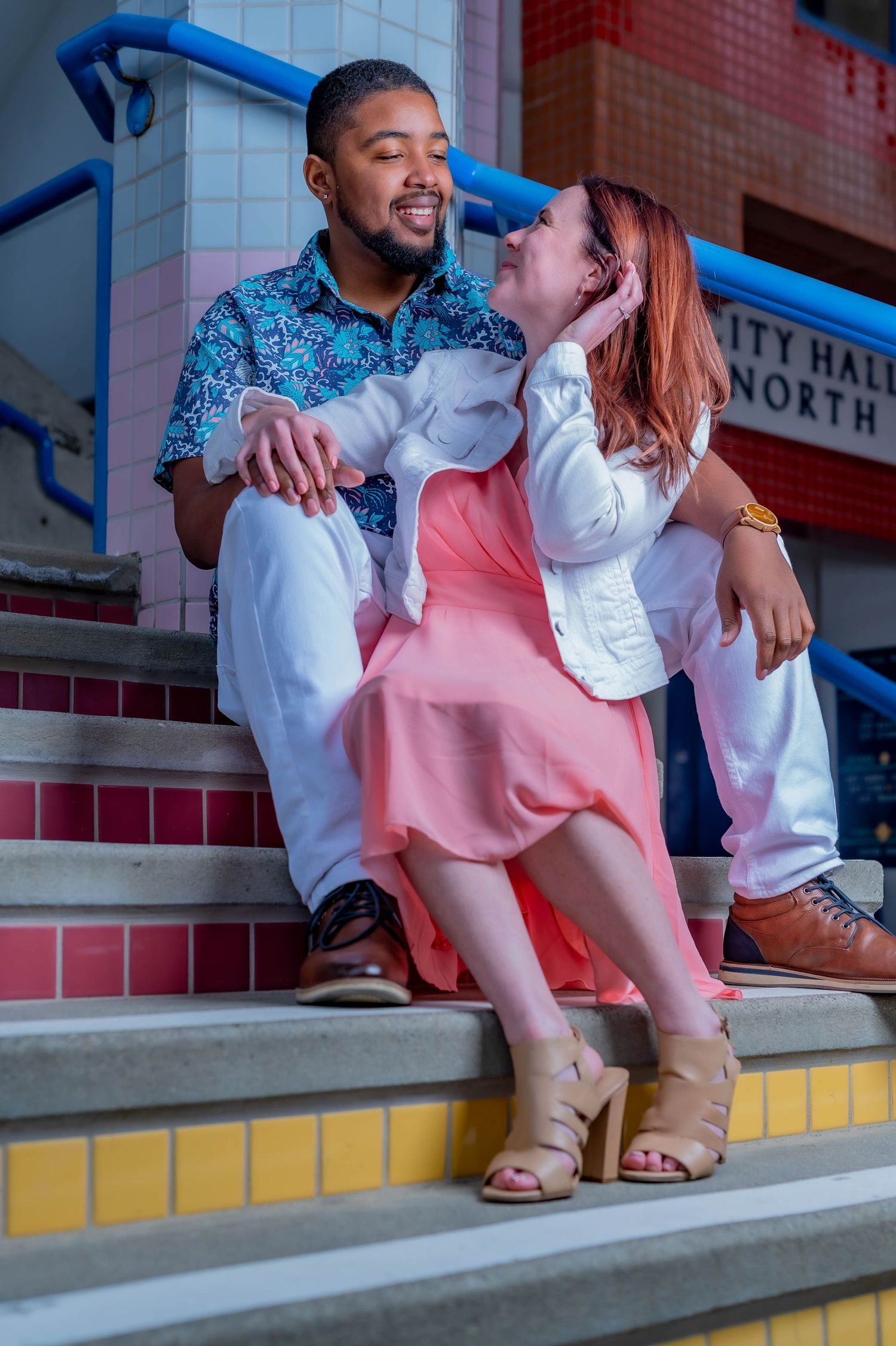 Happy couple sitting on colorful steps sharing a romantic moment.
