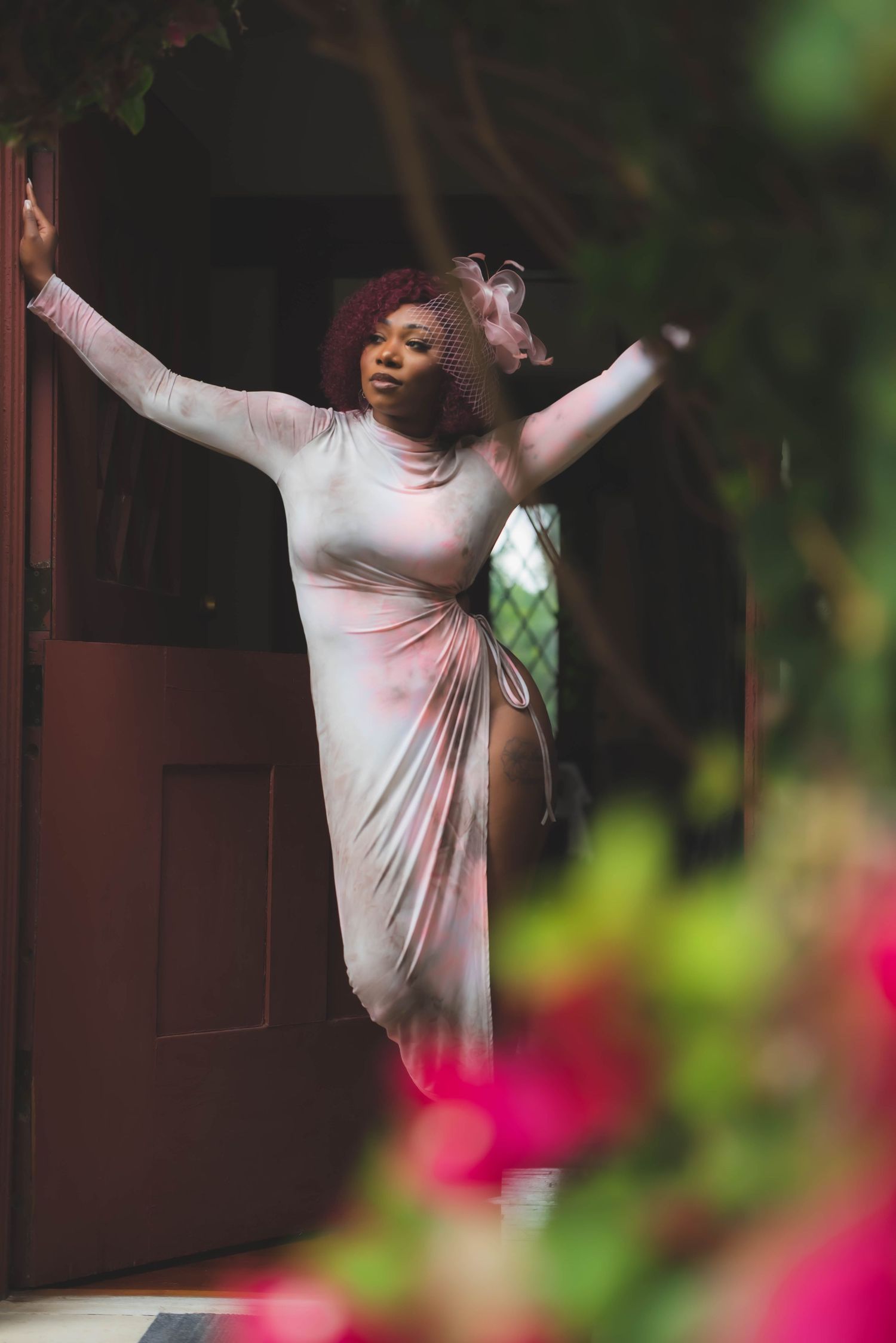 A dancer in a flowing white dress poses gracefully in a doorway surrounded by flowers.
