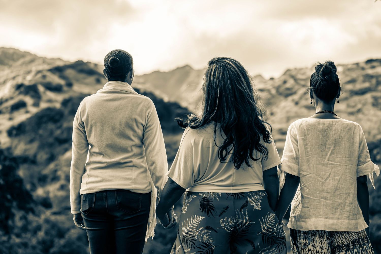 Silhouettes of people standing together against a scenic mountain backdrop at sunset.