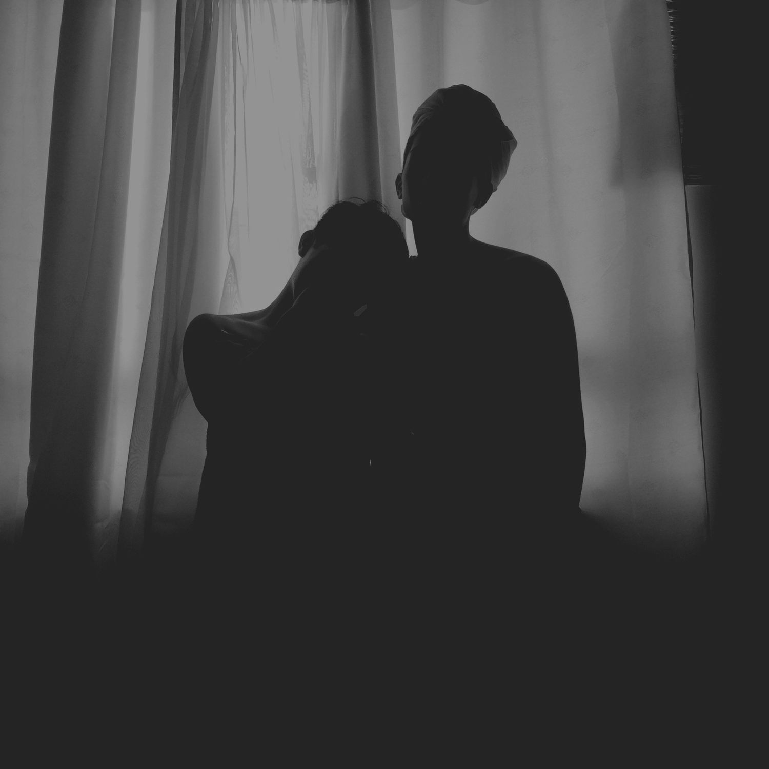 Dark silhouettes of figures against a curtained window creating an eerie atmosphere.