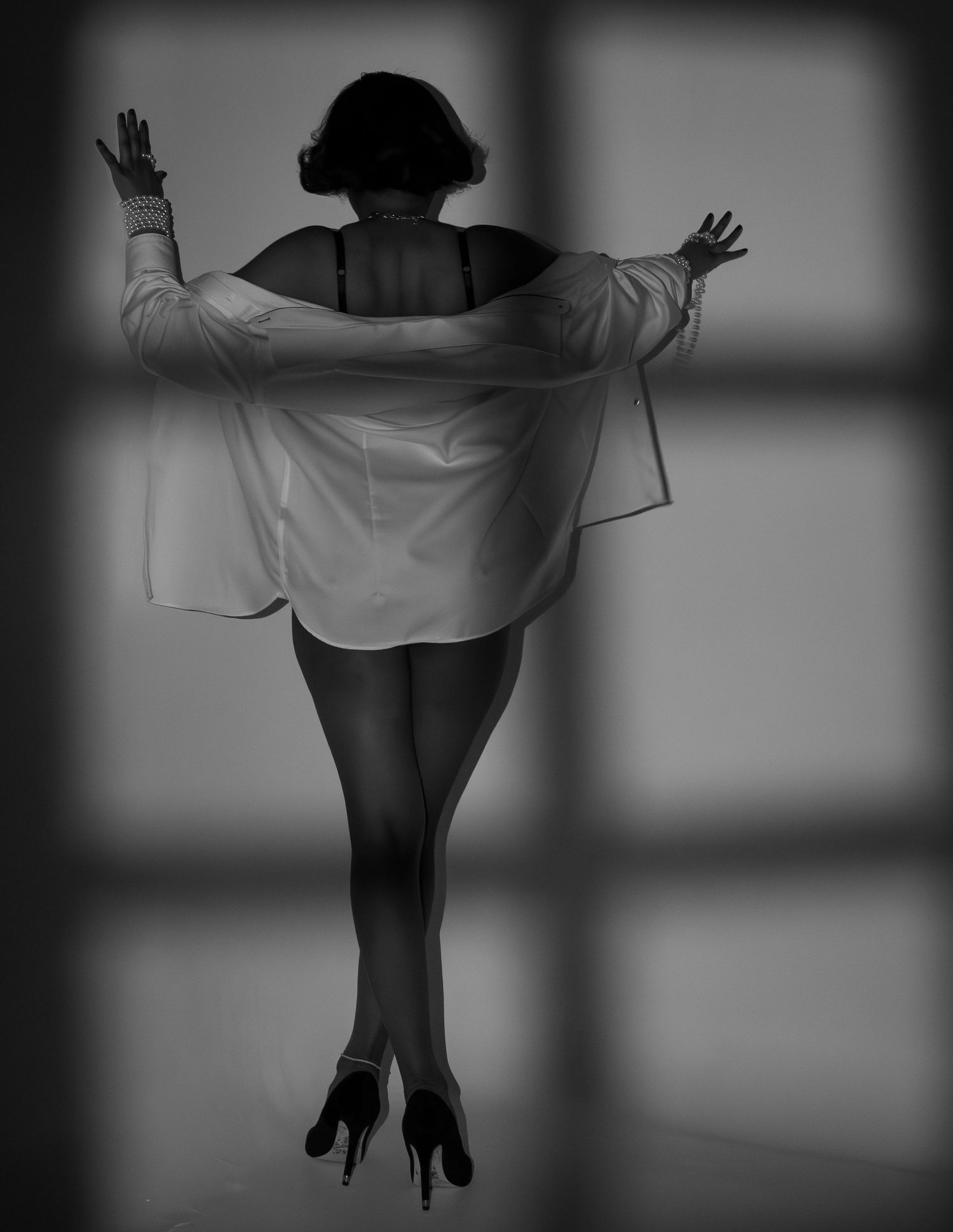 Dramatic black and white silhouette of a person in a dress standing with arms outstretched.