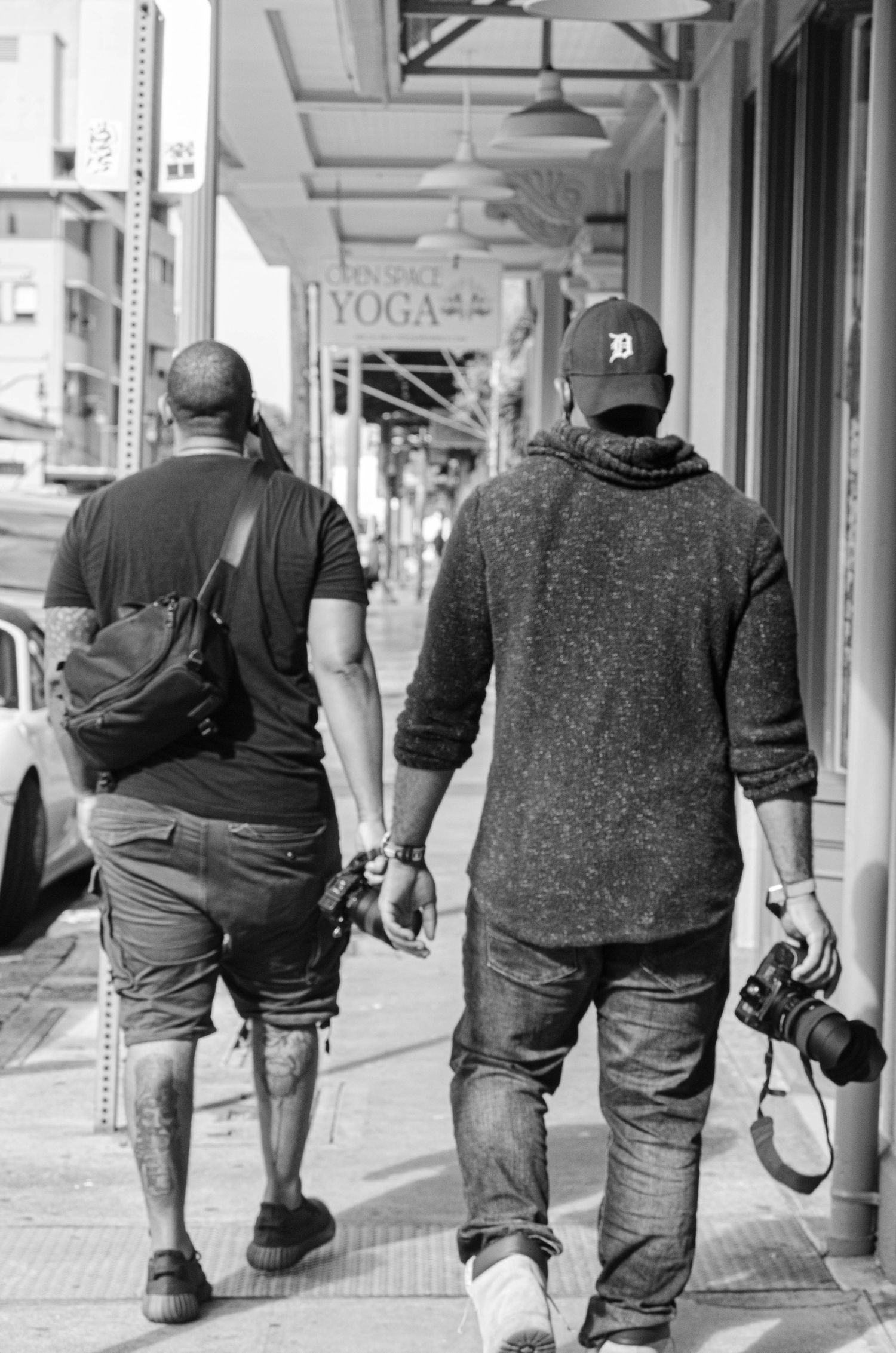 Group of people walking down a city sidewalk past a yoga studio sign.